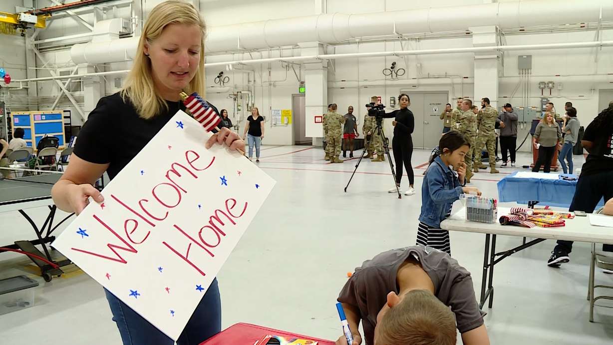 Ashley Schoolcraft helping her son, Adam, create “welcome home” signs at Hill Air Force Base Saturday.