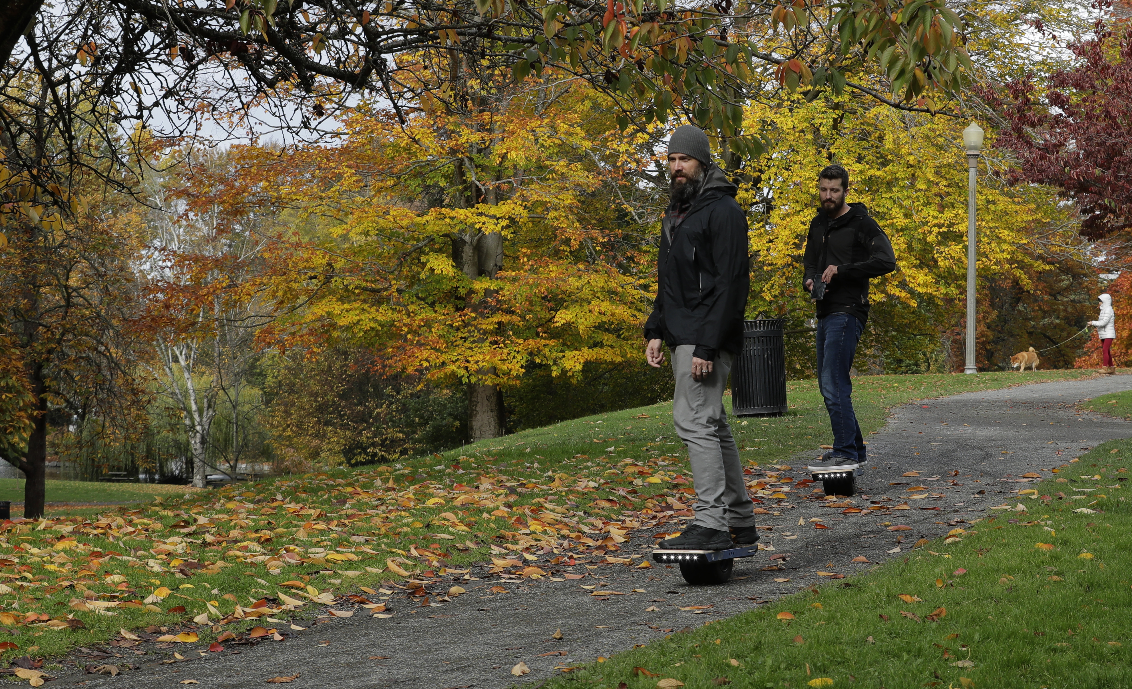 Two people ride Onewheels through Wright Park in Tacoma, Wash., on Oct. 26, 2018. All models of Onewheel self-balancing electric skateboards are under recall after at least four deaths and multiple injuries were reported in recent years.