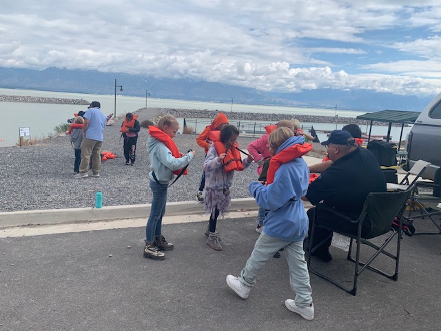 Students are taught by the Coast Guard how to put on different types of life jackets in order to keep themselves safe in the water. The activity was part of a fourth grade field trip on the shore of Utah Lake in Saratoga Springs on Tuesday.