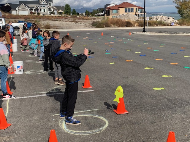 A group of fourth graders practices how to use a fishing pole by catching plastic fish in a parking lot. The activity was part of a fourth grade field trip on the shore of Utah Lake in Saratoga Springs on Tuesday.