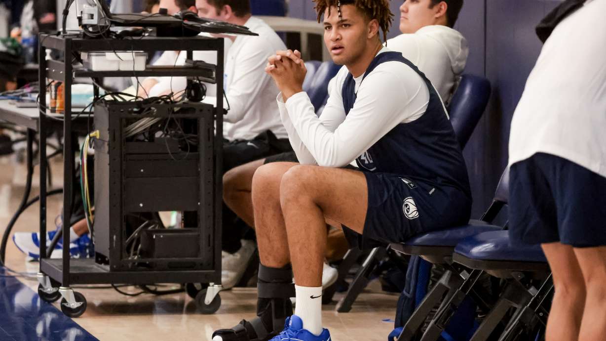 Marcus Adams Jr. sits on the sideline wearing a boot on his foot during BYU basketball practice at the Marriott Center Annex Court in Provo on Tuesday, Oct. 3, 2023.