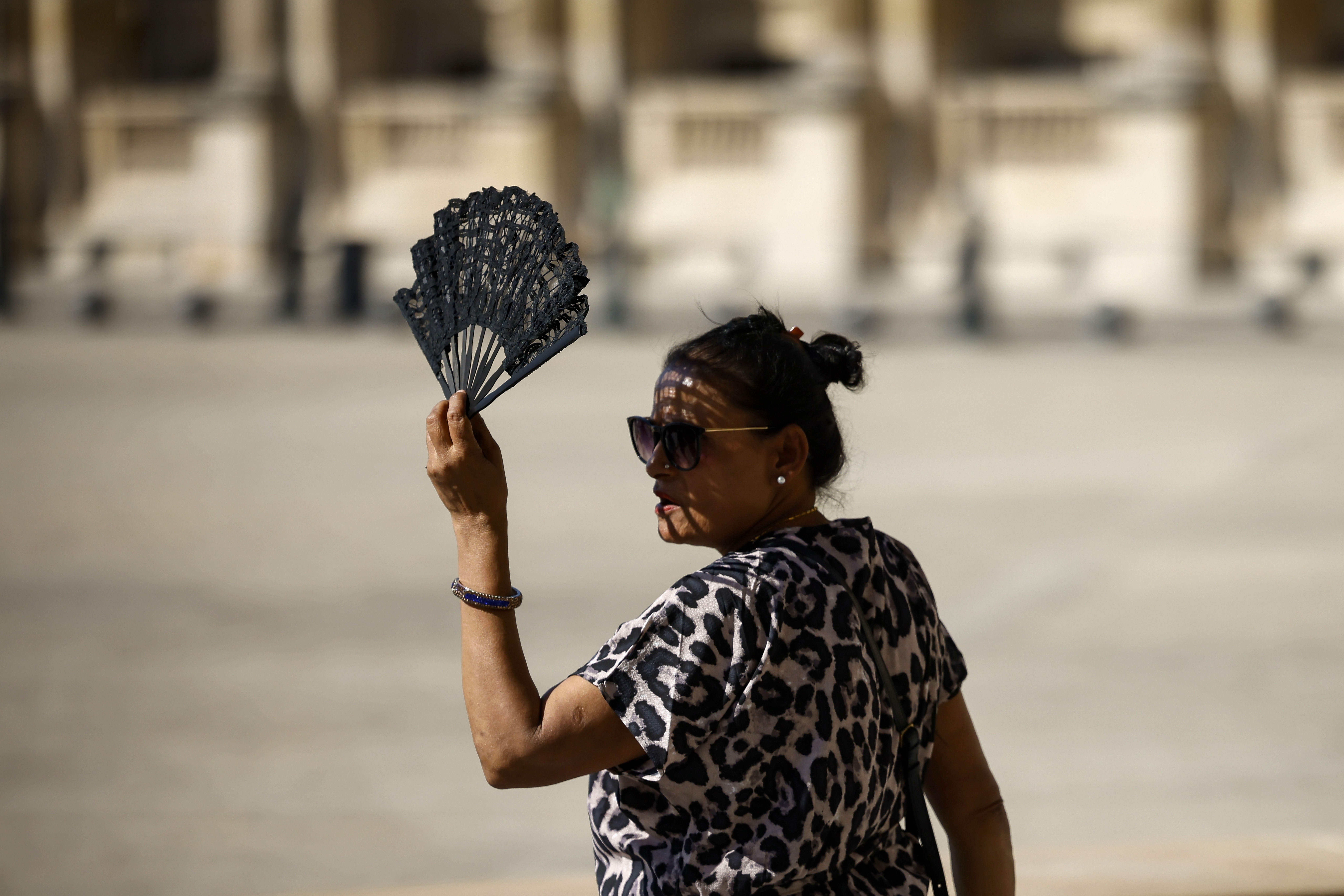 A woman uses a fan in the courtyard of the Louvre museum, Sept. 7, in Paris. After a summer of record-smashing heat, warming somehow got even worse in September as Earth set a new mark for how far above normal temperatures were.