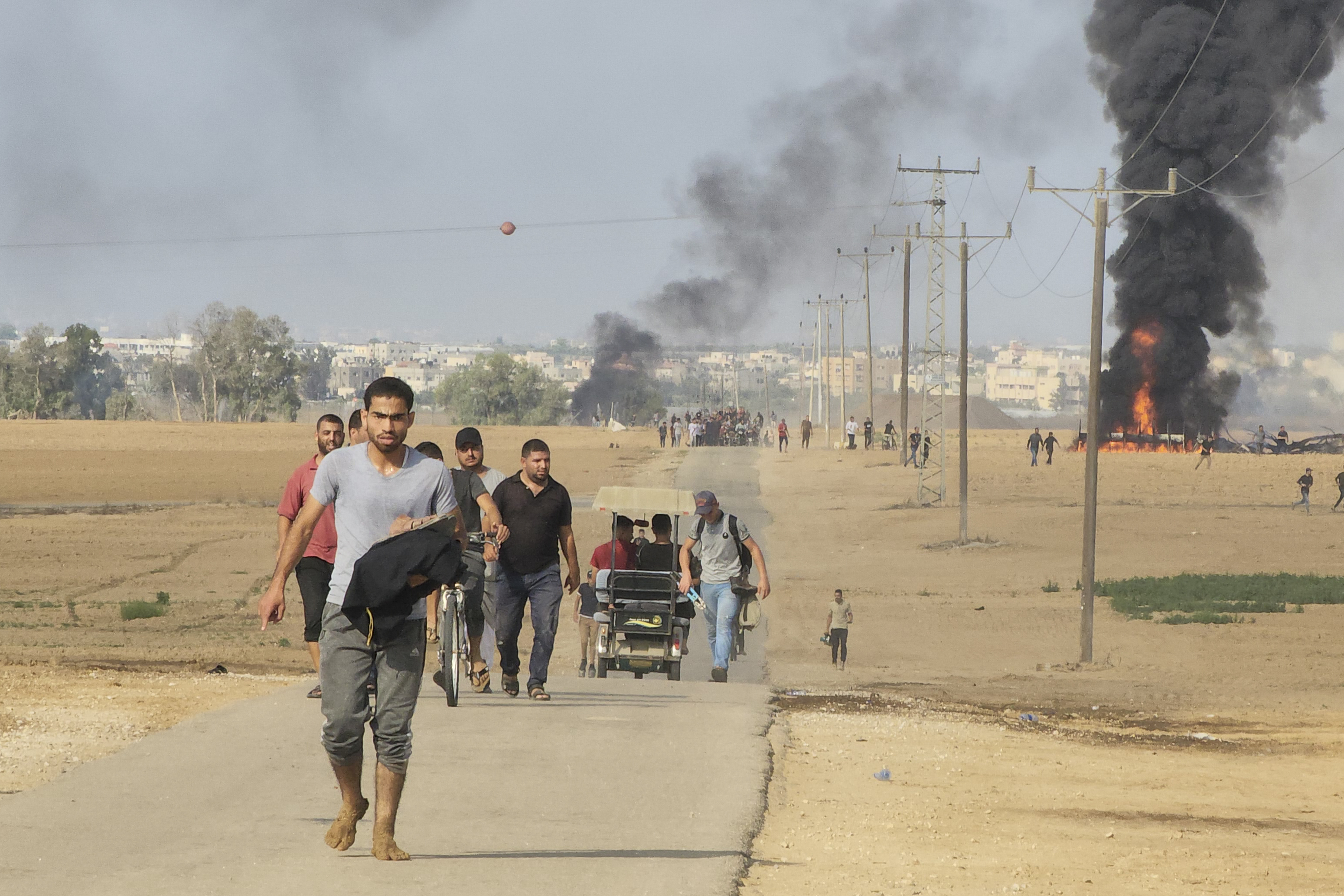 Palestinians walk away from the kibbutz of Kfar Azza, Israel, near the fence with the Gaza strip on Saturday. The militant Hamas rulers of the Gaza Strip carried out an unprecedented, multi-front attack on Israel at daybreak Saturday.