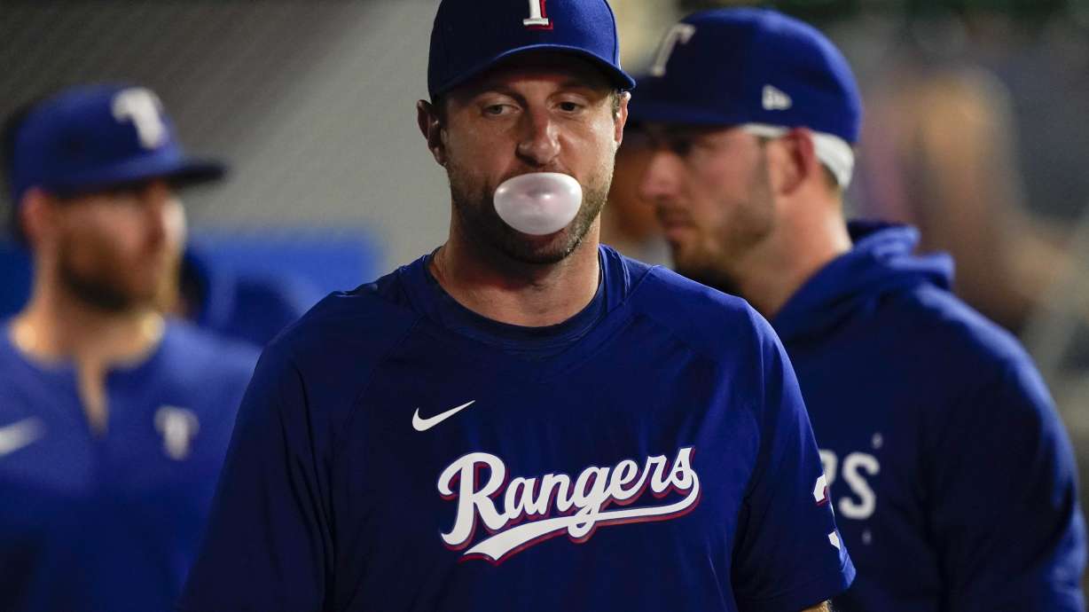 Texas Rangers pitcher Max Scherzer blows a gum bubble in the dugout during the second inning of a baseball game against the Los Angeles Angels, Monday, Sept. 25, 2023, in Anaheim, Calif.
