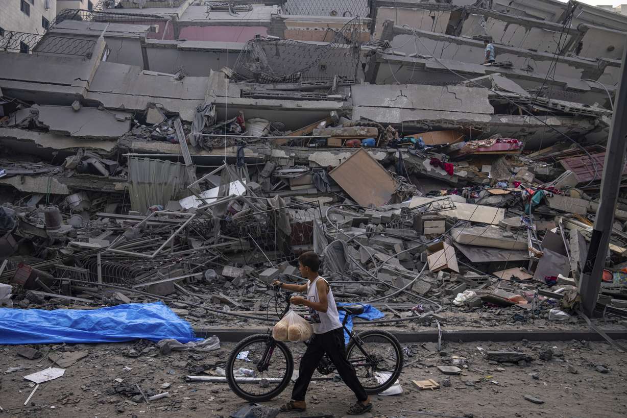 Palestinians kid walks by the rubble of a building after it was struck by an Israeli airstrike, in Gaza City, Sunday. The militant Hamas rulers of the Gaza Strip carried out an unprecedented, multi-front attack on Israel at daybreak Saturday, firing thousands of rockets as dozens of Hamas fighters infiltrated the heavily fortified border in several locations by air, land, and sea, killing hundreds and taking captives. Palestinian health officials reported scores of deaths from Israeli airstrikes in Gaza.