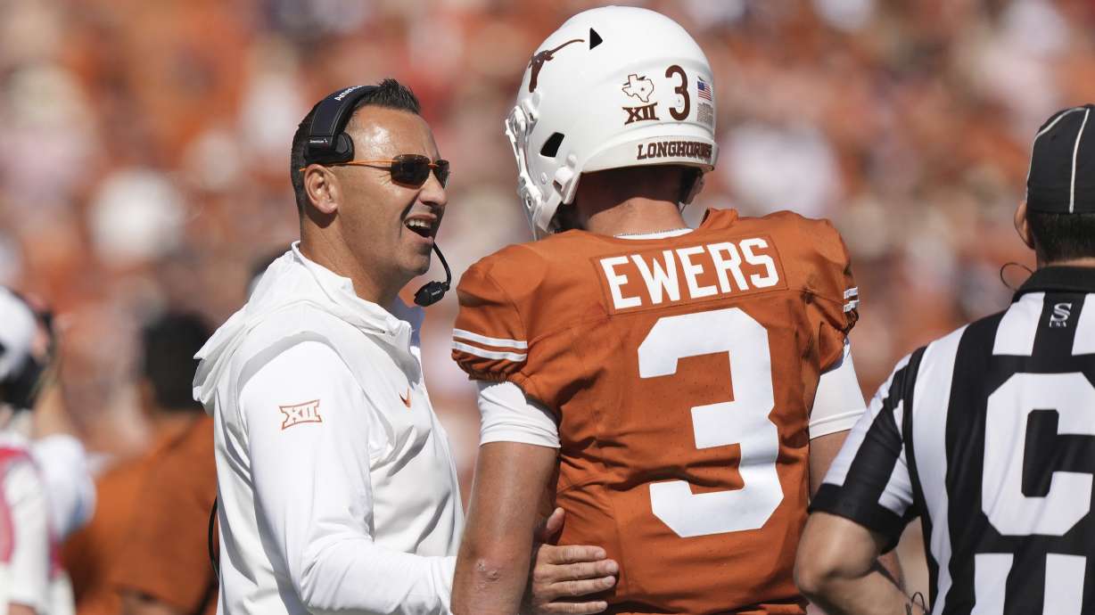 Texas head coach Steve Sarkisian, left, confers with quarterback Quinn Ewers (3) during the first half of an NCAA college football game against Oklahoma at the Cotton Bowl in Dallas, Saturday, Oct. 7, 2023.