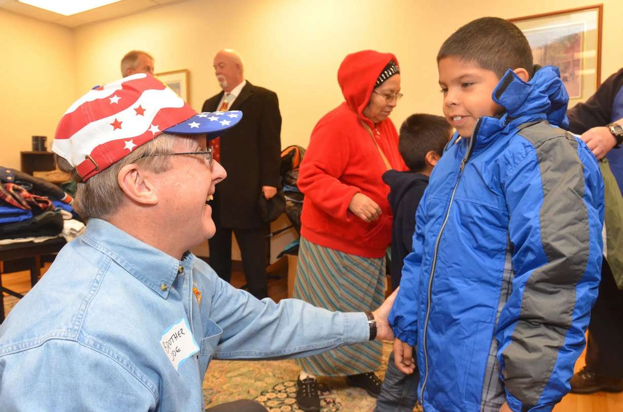 Jerry Angus of the Knights of Columbus helps fit a child with a coat during the fraternal organization's Coats for Kids campaign in this undated photo.