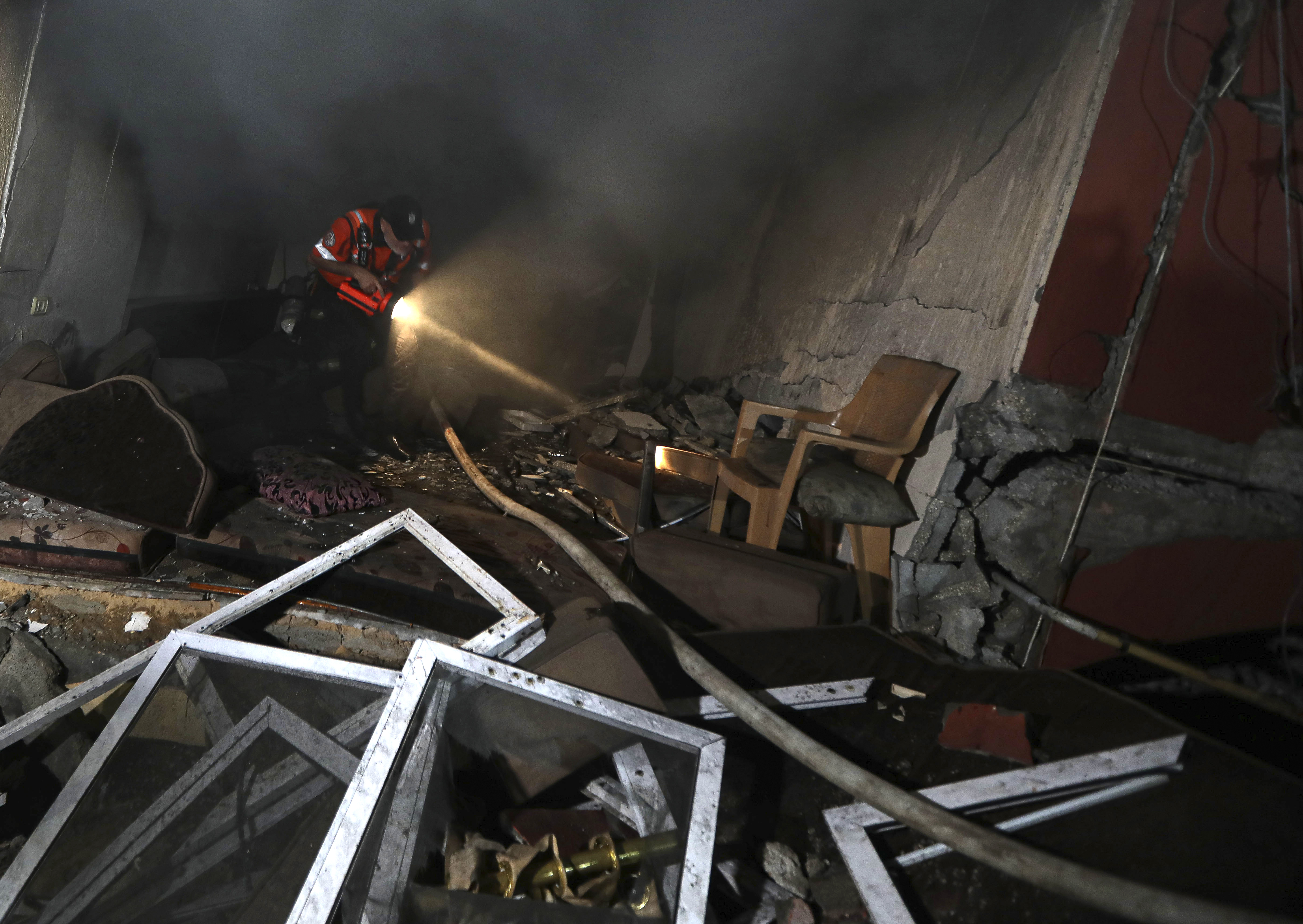 Palestinian civil defense crew looks through a house that was hit by an Israeli airstrike in Khan Younis, southern Gaza Strip, Sunday.