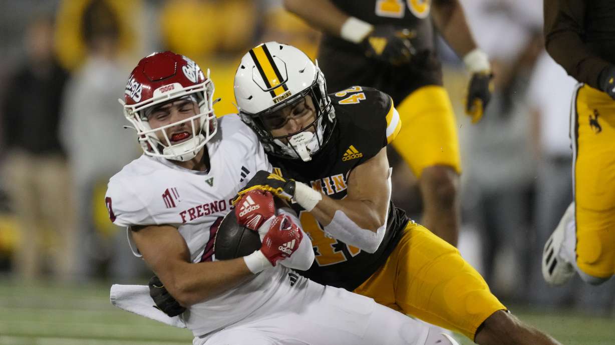 Fresno State wide receiver Mac Dalena, left, is pulled down by Wyoming safety Isaac White during the second half of an NCAA college football game Saturday, Oct. 7, 2023, in Laramie, Wyo.