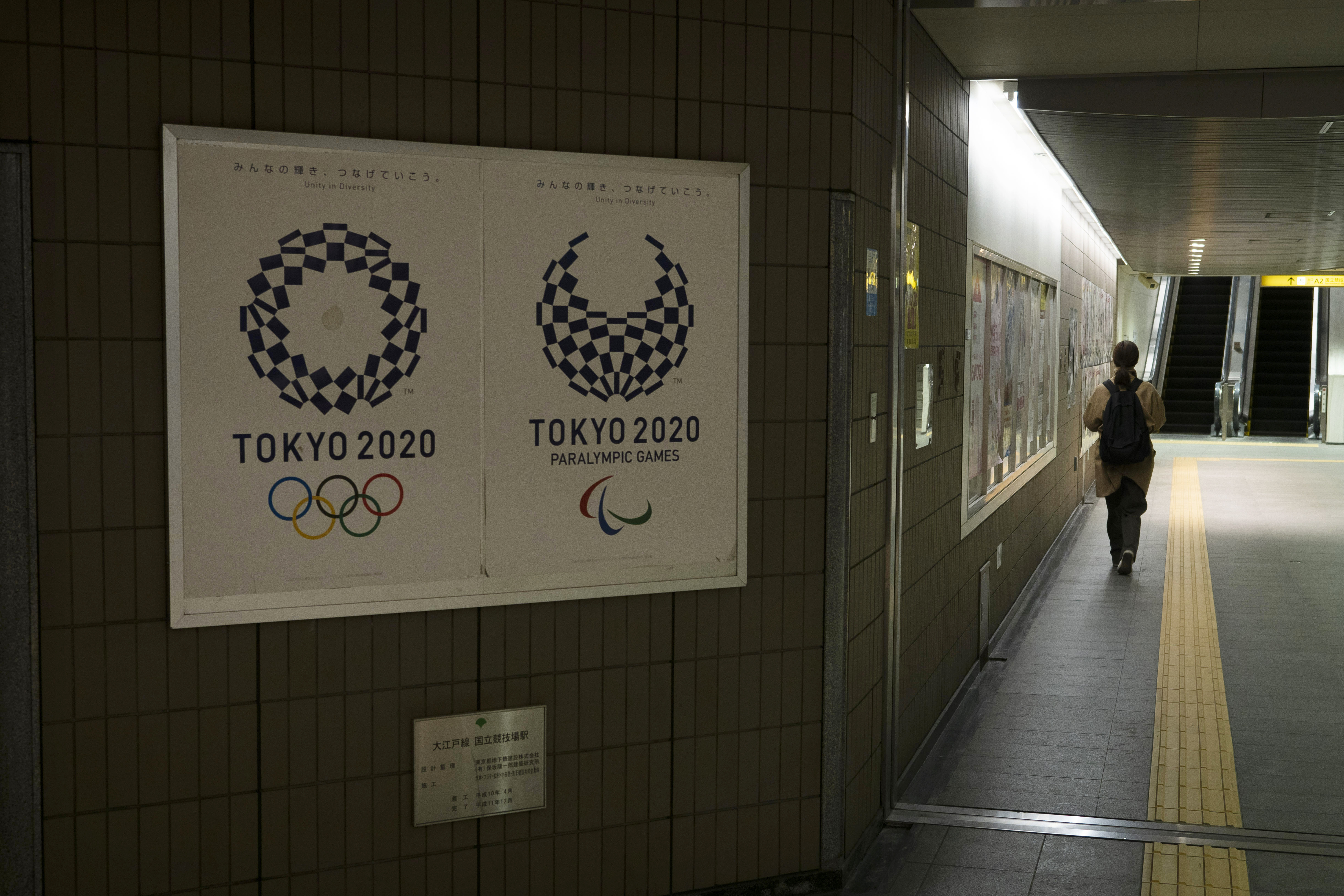 FILE - A commuter leaves a train station adorned with posters promoting the Tokyo 2020 Olympics in Tokyo, on March 23, 2020. An executive at Japanese publishing house Kadokawa was found guilty Tuesday, Oct. 10, 2023 of bribing a former Tokyo Olympics organizing committee member. 