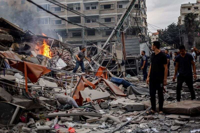 Palestinians watch a fire burn among the rubble of a damaged residential building, in the aftermath of Israeli strikes, in Gaza City, Tuesday.