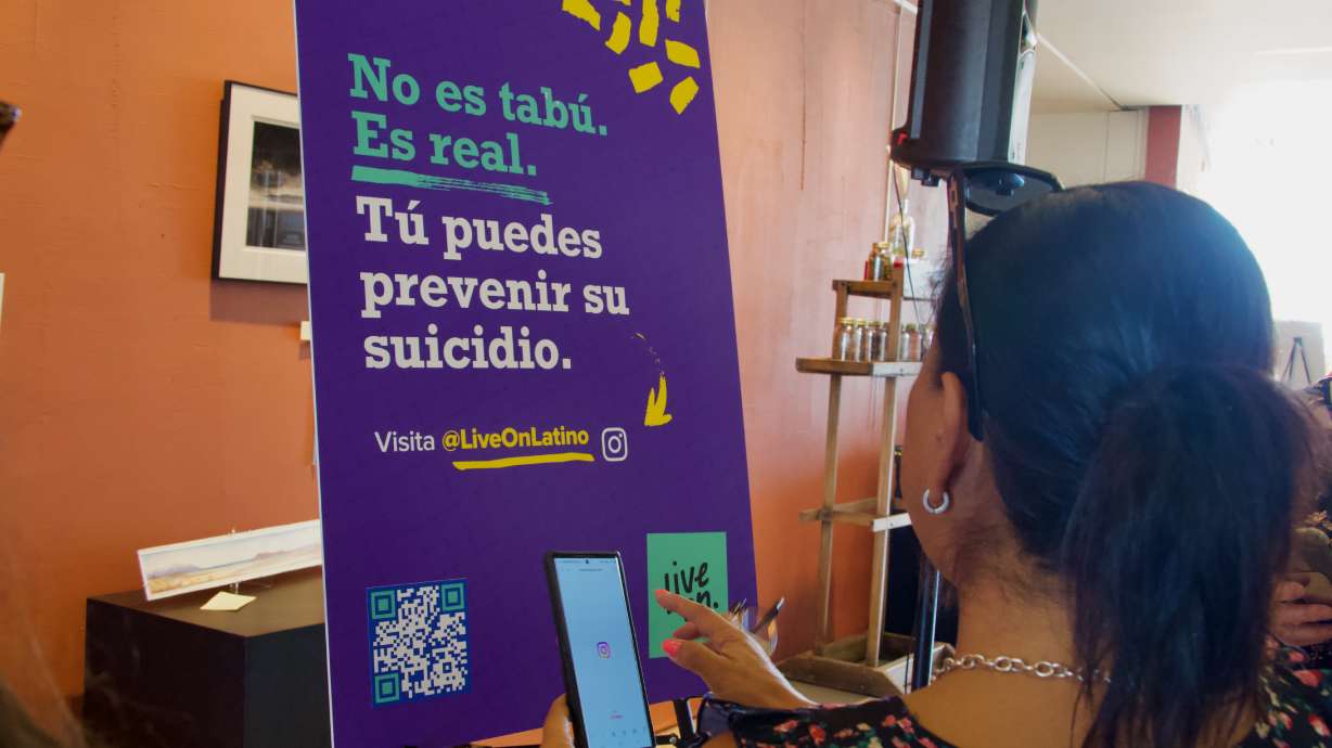 Mariana Aguila scans a QR code on a poster promoting Utah's new Live on Latino suicide prevention resources at the Sorensen Unity Center in Salt Lake City on Tuesday.