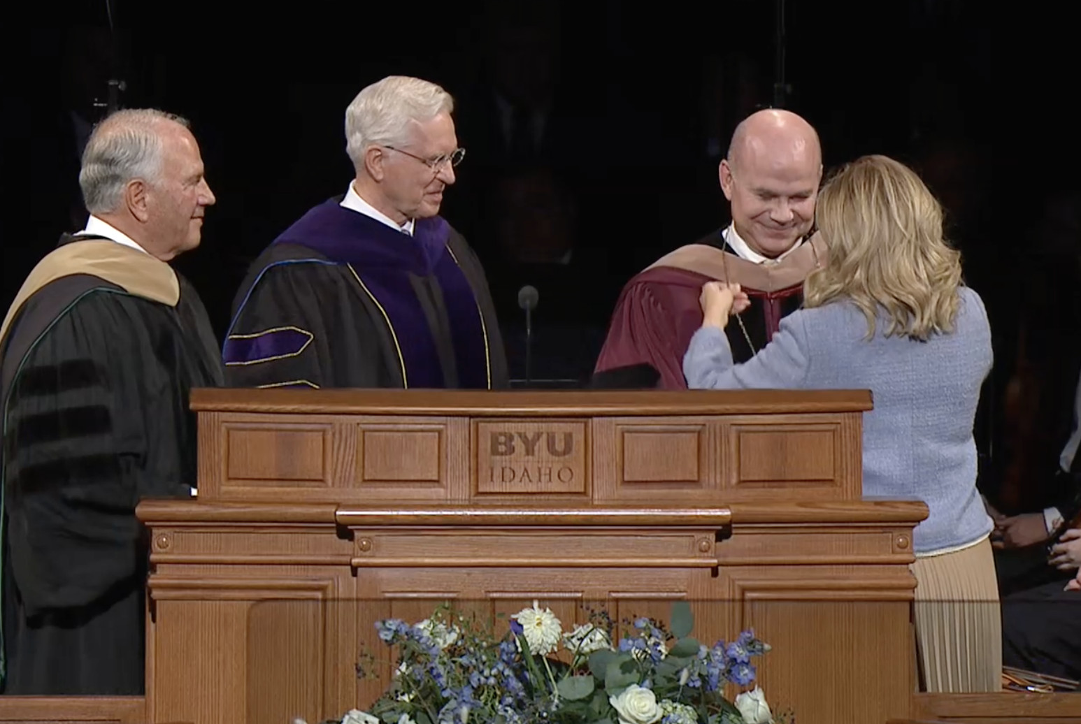 Jennifer Meredith places a medallion around the neck of her husband, new BYU-Idaho President Alvin F. Meredith, after he was formally installed by Elders Ronald A. Rasband, left, and D. Todd Christofferson at the BYU-Idaho Center in Rexburg, Idaho, on Tuesday.