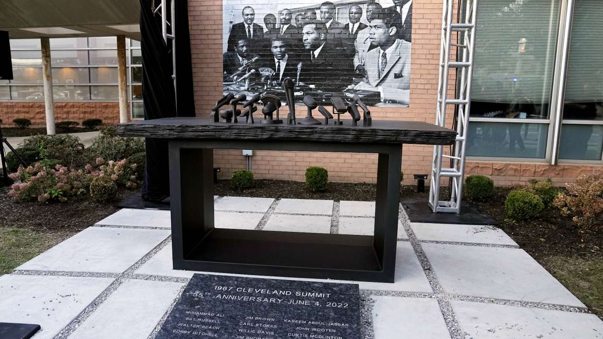 A sculpture commemorating the 1967 Cleveland summit with Muhammad Ali, Jim Brown and others is unveiled Wednesday, Oct. 11, 2023, in Cleveland. The sculpture is a representation of the press conference table where the Black athletes sat; at photo of the event is at rear.