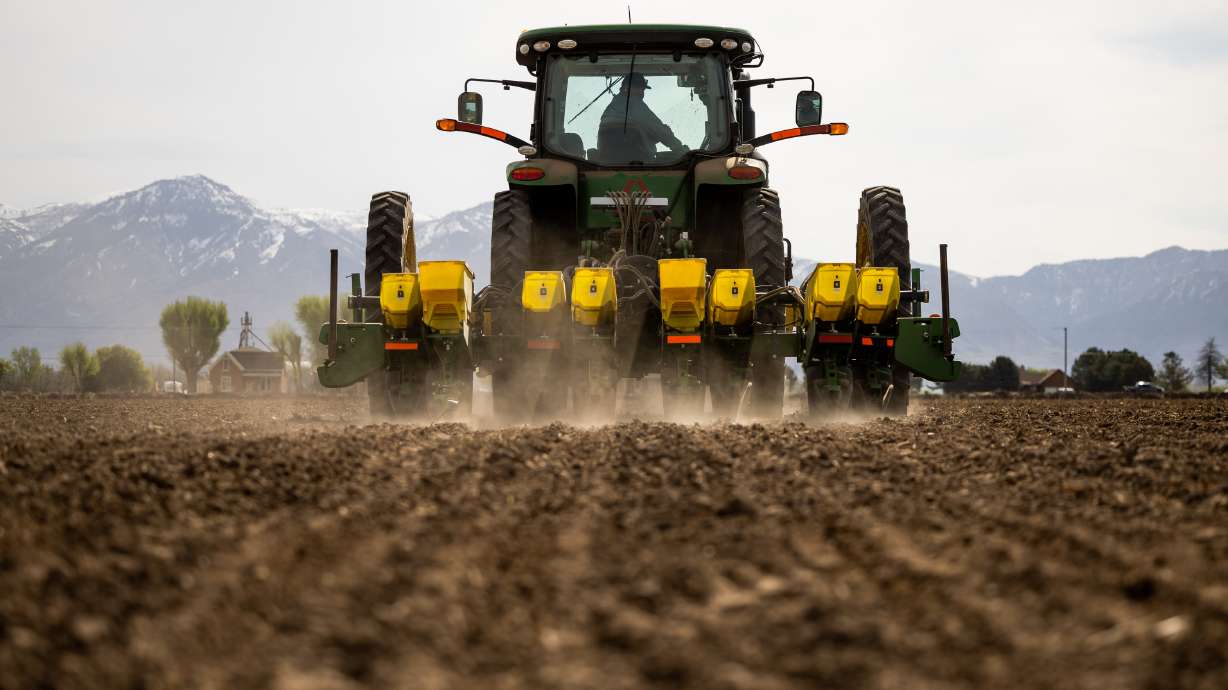 A Utah farmer works on a tractor while planting a field with corn in Ogden on May 4. Lawmakers are considering a bill to give farmers a "right to repair" farm equipment.