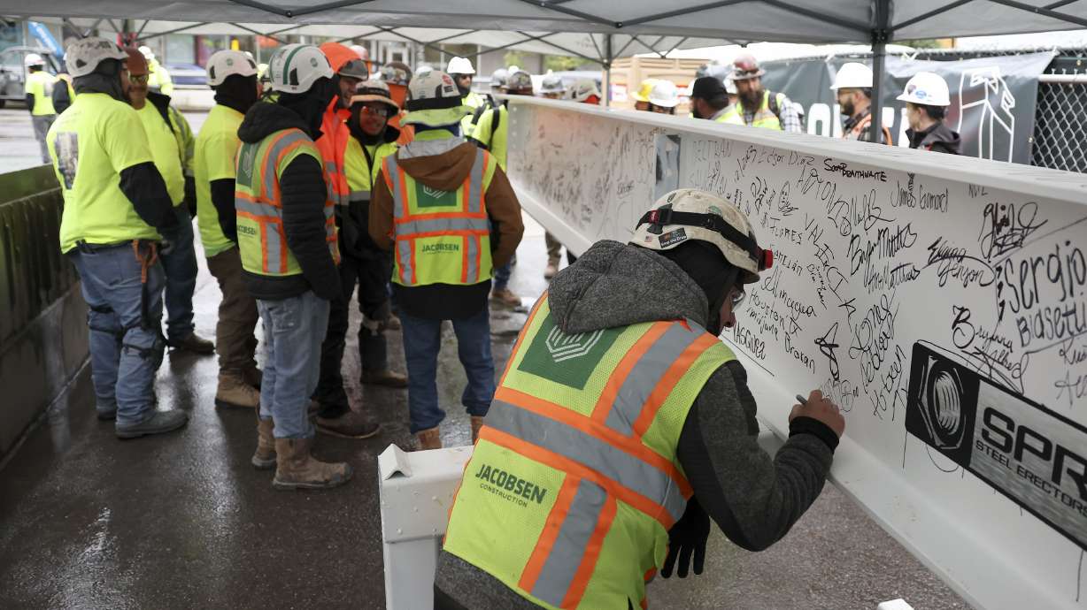 Construction workers sign the final steel beam before its ceremonial placement atop the 40th floor of Astra Tower in Salt Lake City on Thursday. The 40-story tower in Salt Lake City's downtown will be Utah’s tallest high-rise at 450 feet.