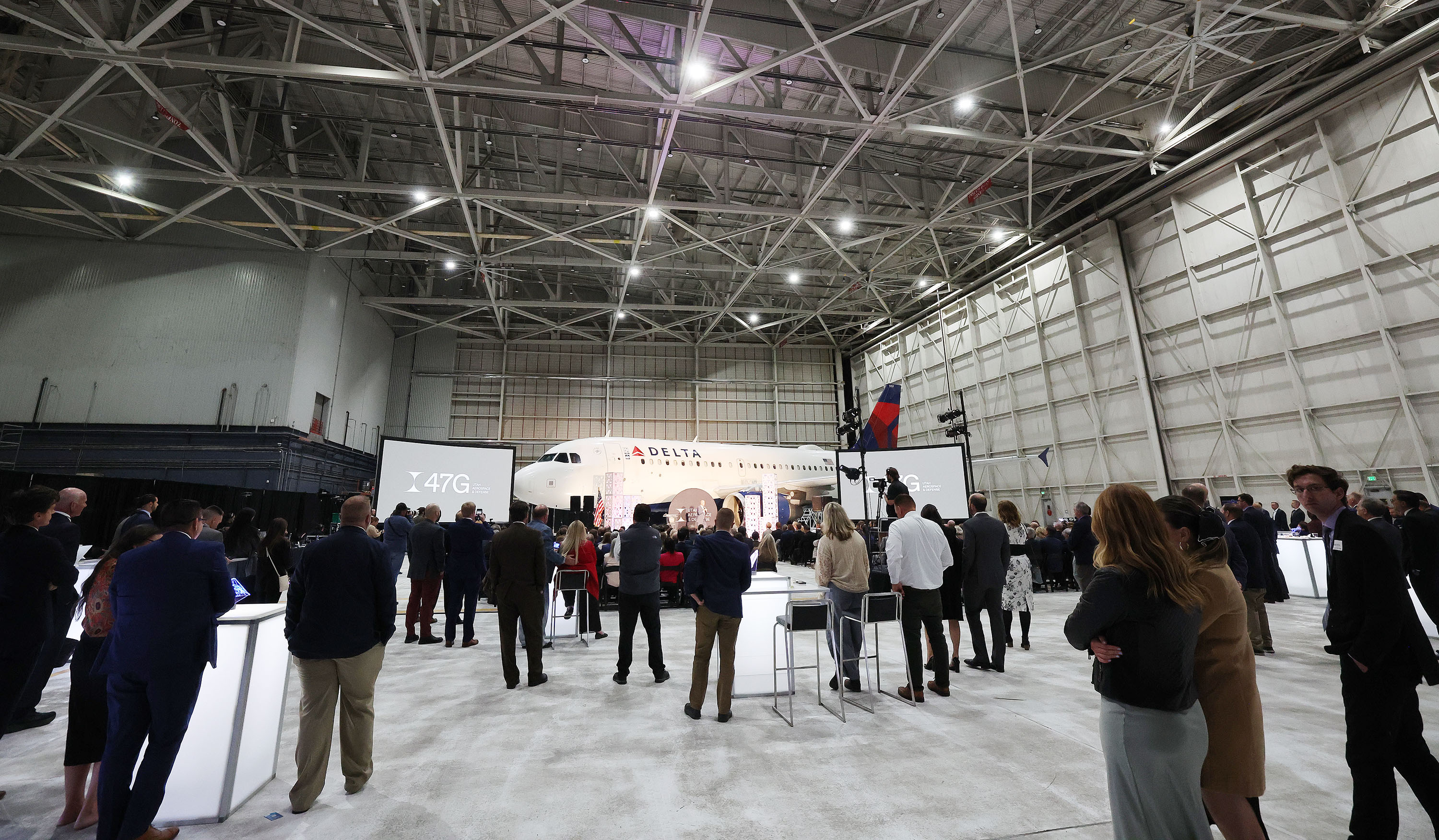 Attendees listen to the program in the Delta hangar in Salt Lake City on Thursday as Utah Aerospace and Defense invests in artificial intelligence and semiconductor research and rebrands.