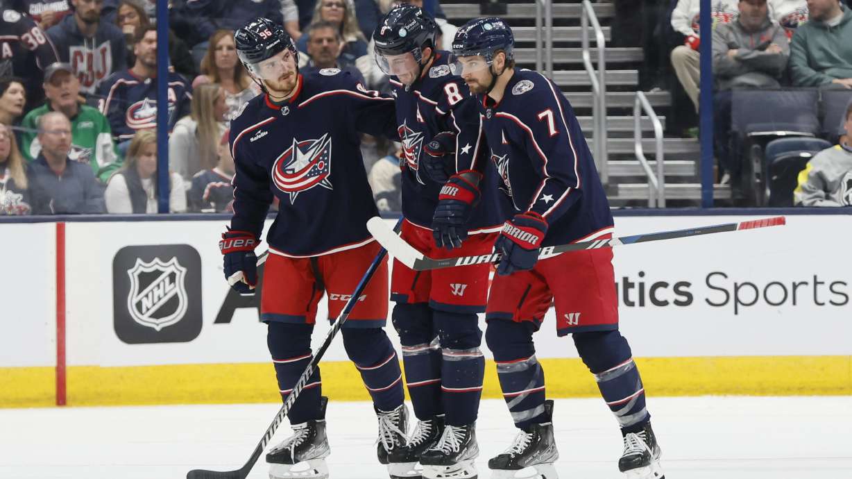 Columbus Blue Jackets' Jack Roslovic, left, and Sean Kuraly, right, help Zach Werenski off the ice after Werenski during the second period of the team's NHL hockey game against the Philadelphia Flyers on Thursday, Oct. 12, 2023, in Columbus, Ohio.