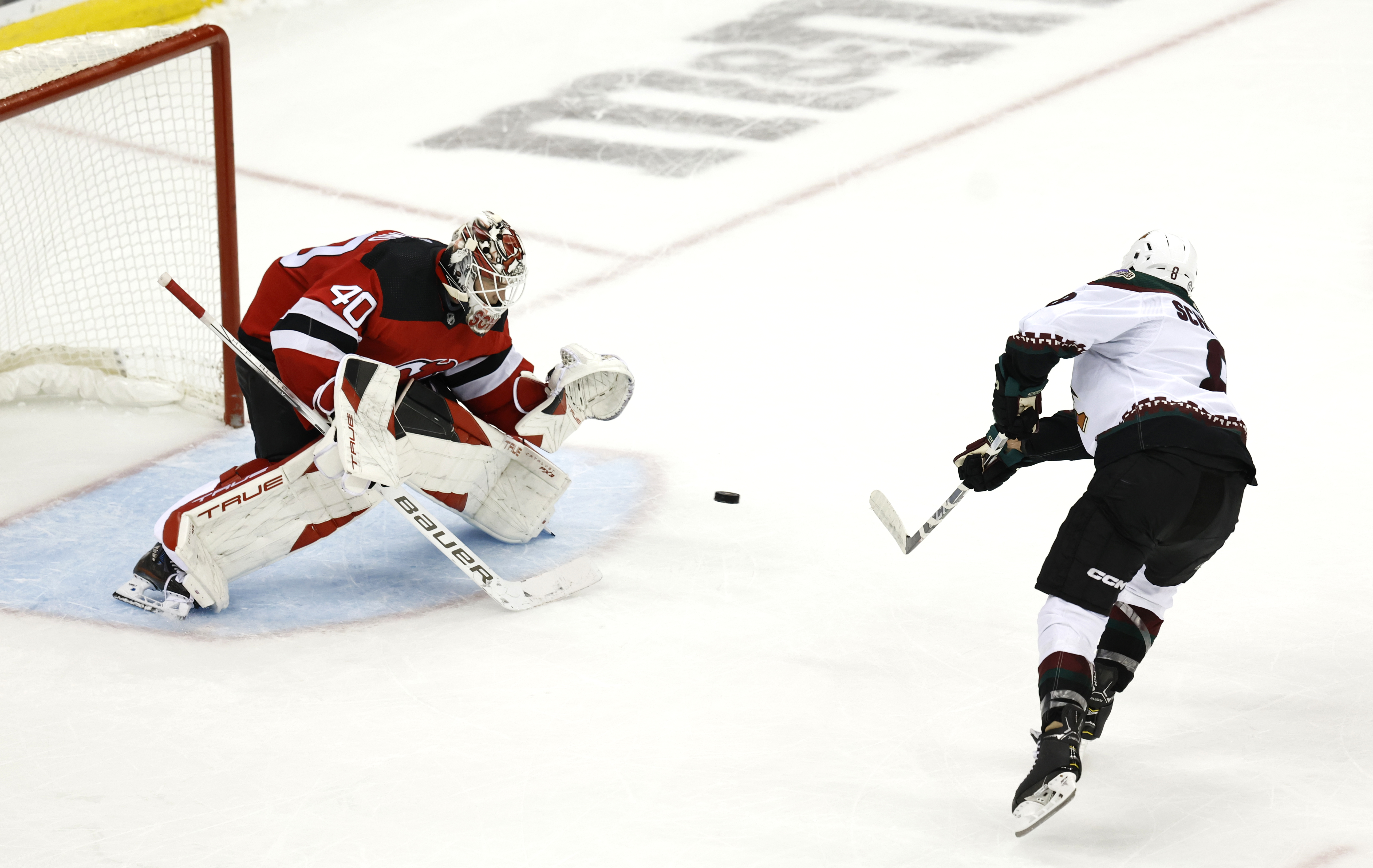 Arizona Coyotes center Nick Schmaltz, right, scores against New Jersey Devils goaltender Akira Schmid (40) during a shootout of an NHL hockey game Friday, Oct. 13, 2023, in Newark, N.J.
