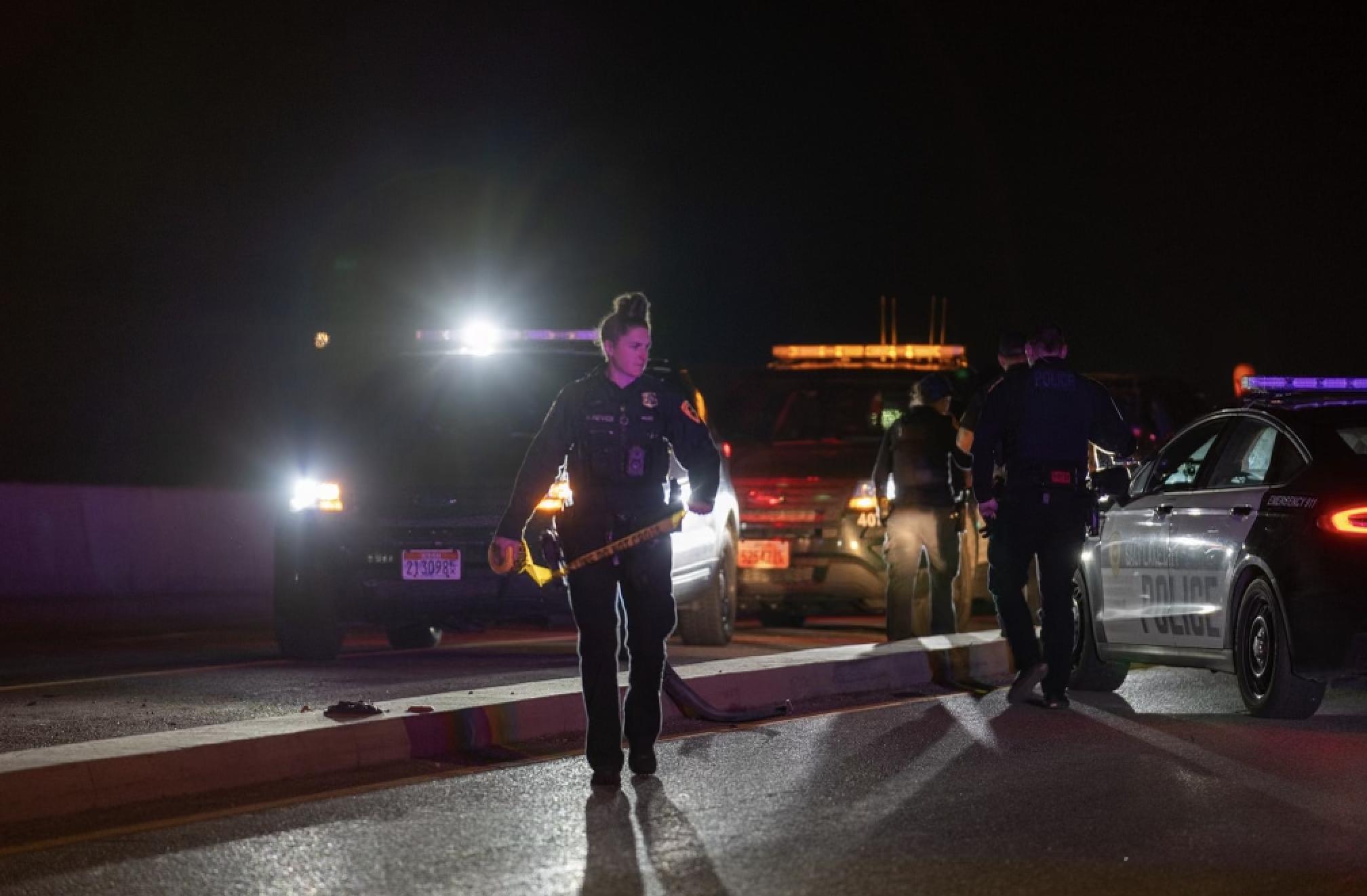 A Salt Lake police officer prepares to run yellow crime scene tape across Redwood Road near 200 South after a deadly crash Friday.