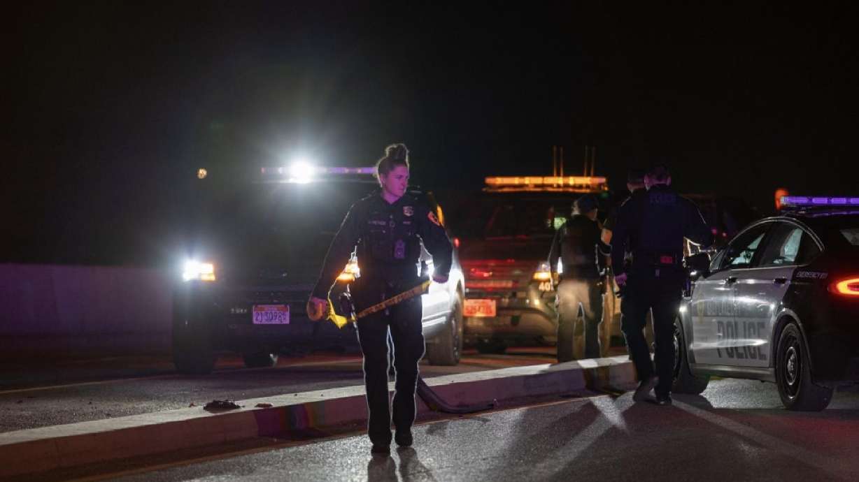 A Salt Lake police officer prepares to run yellow crime scene tape across Redwood Road near 200 South after a deadly crash Friday.