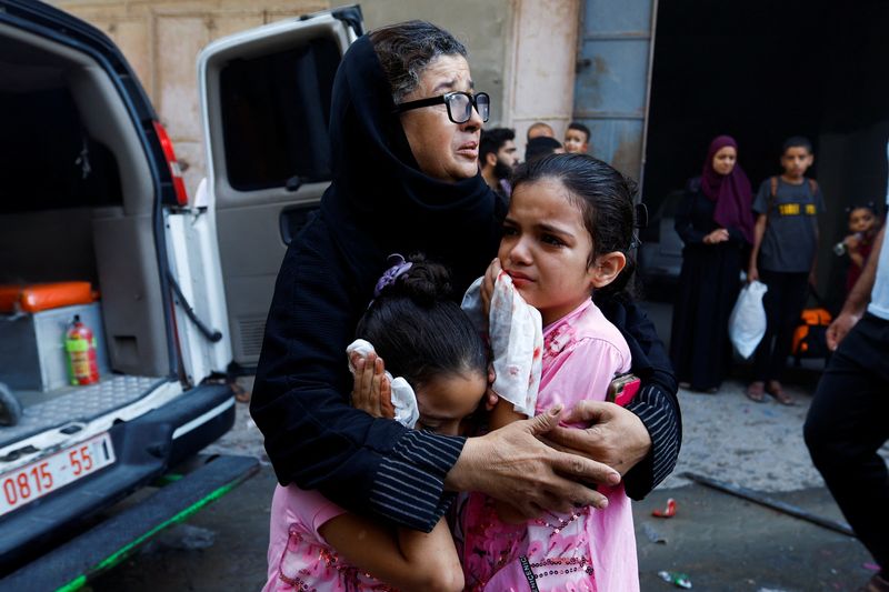 A Palestinian woman and children react in the aftermath of Israeli strikes, in Khan Younis in the southern Gaza Strip, on Friday.