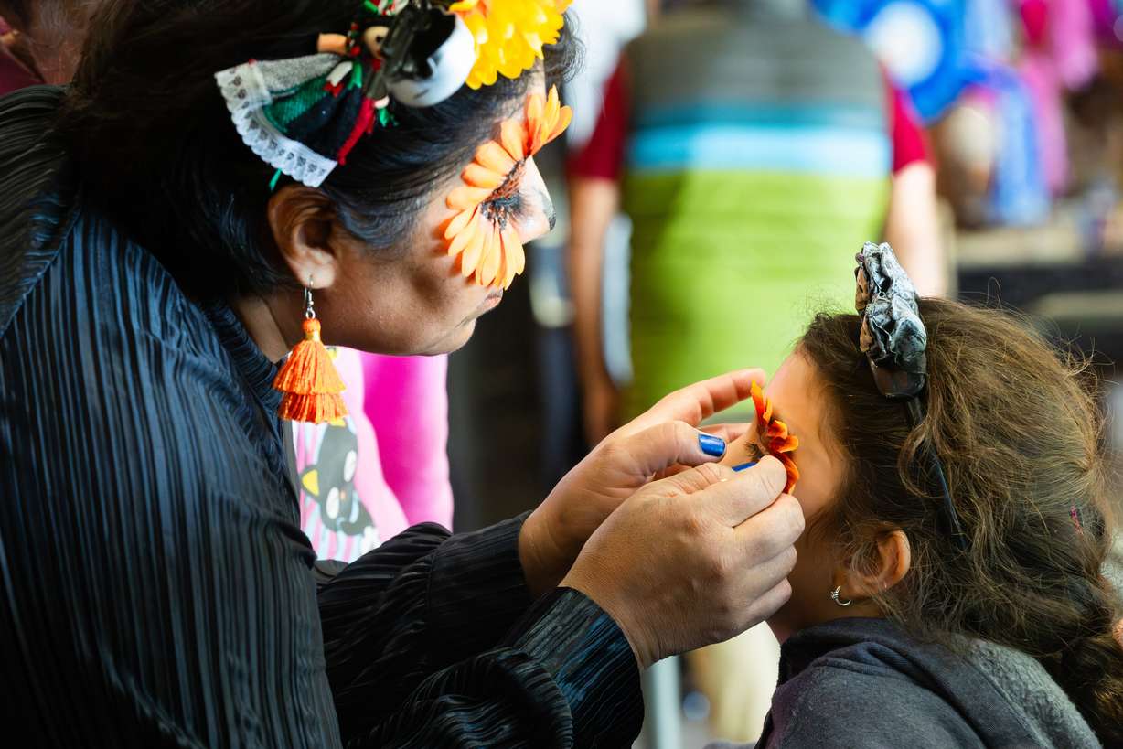 Alexia Bou gets her makeup done by Gabby Romero at the annual Dia de los Muertos celebration hosted by Una Mano Amiga at Trolley Square in Salt Lake City on Saturday.