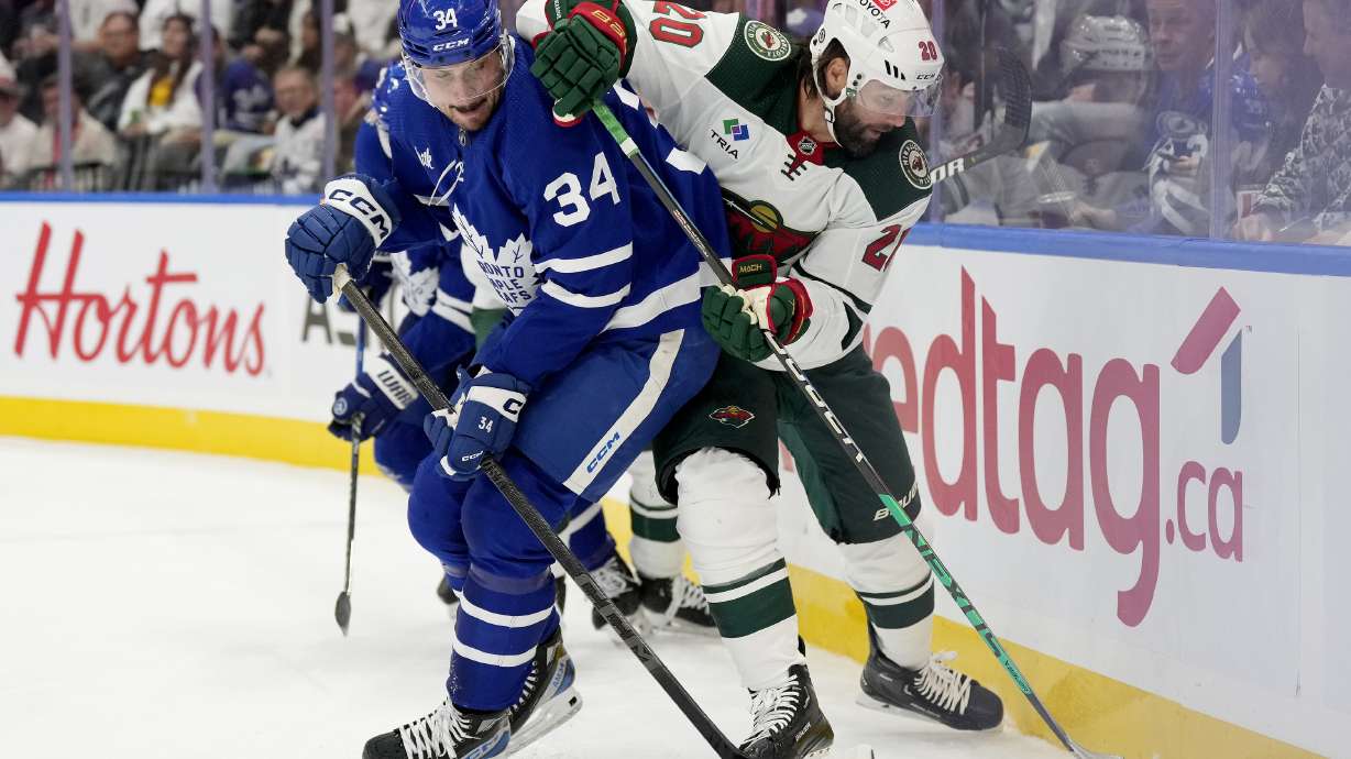 Toronto Maple Leafs center Auston Matthews (34) and Minnesota Wild left wing Pat Maroon (20) vie for control of the puck during the first period of an NHL hockey game in Toronto, Saturday, Oct. 14, 2023.