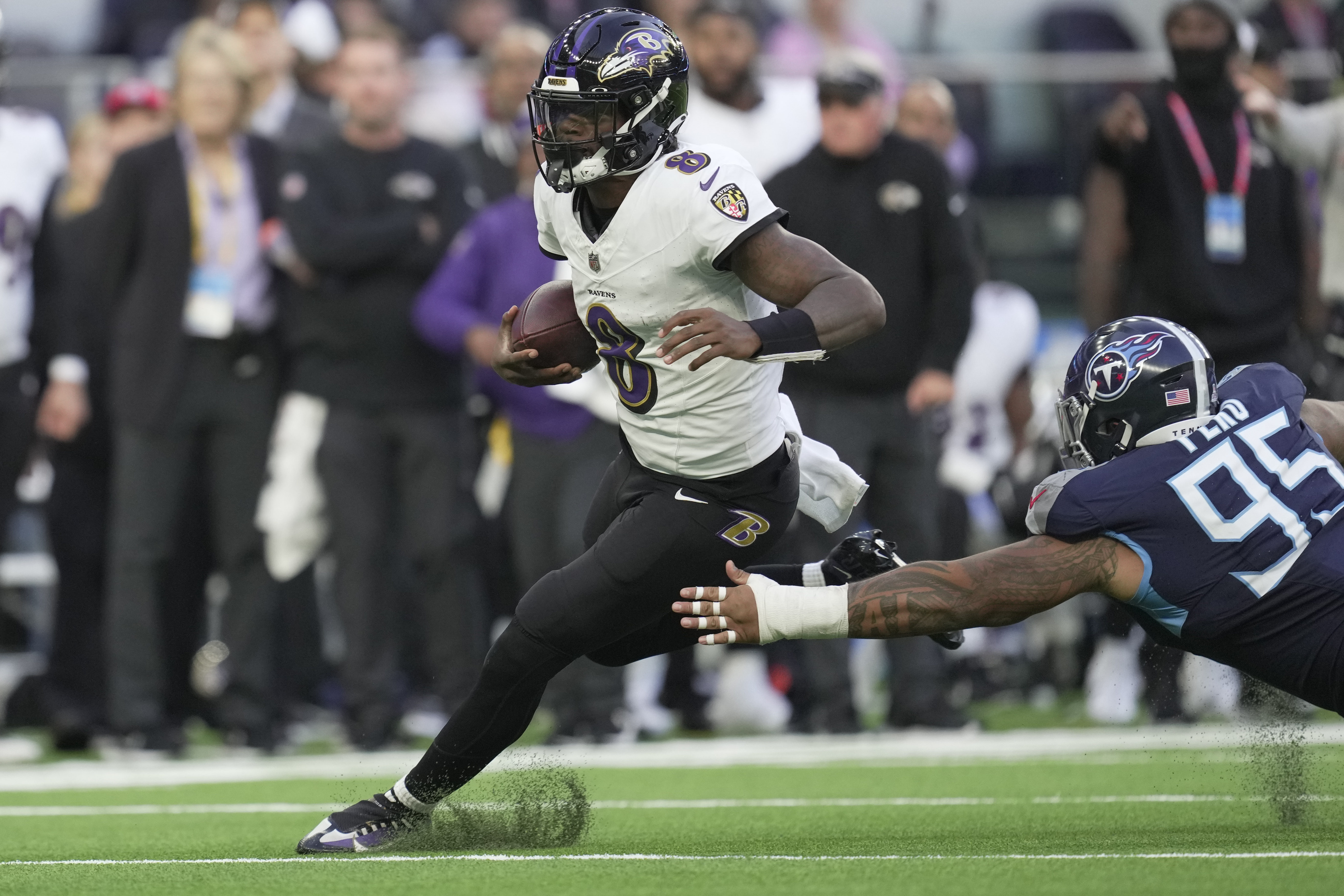 Baltimore Ravens quarterback Lamar Jackson (8) runs the ball past Tennessee Titans defensive tackle Kyle Peko (95) during the second half of an NFL football game Sunday, Oct. 15, 2023, at the Tottenham Hotspur stadium in London. 