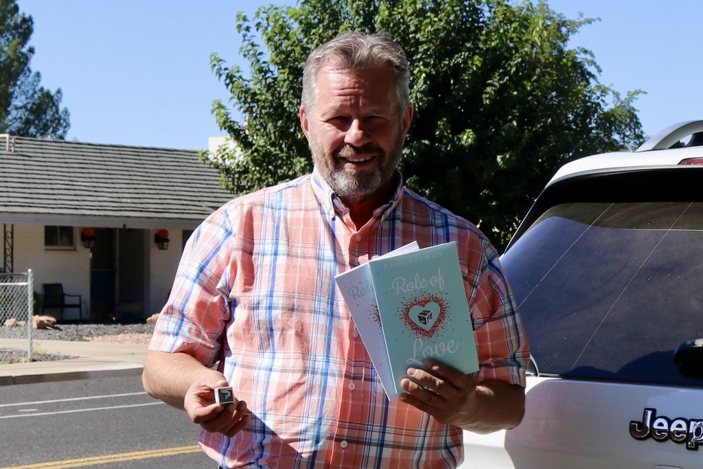 Paul Zolman, owner of Role of Love, takes a photo with his dice, books and journal, St. George, Sept. 25.
