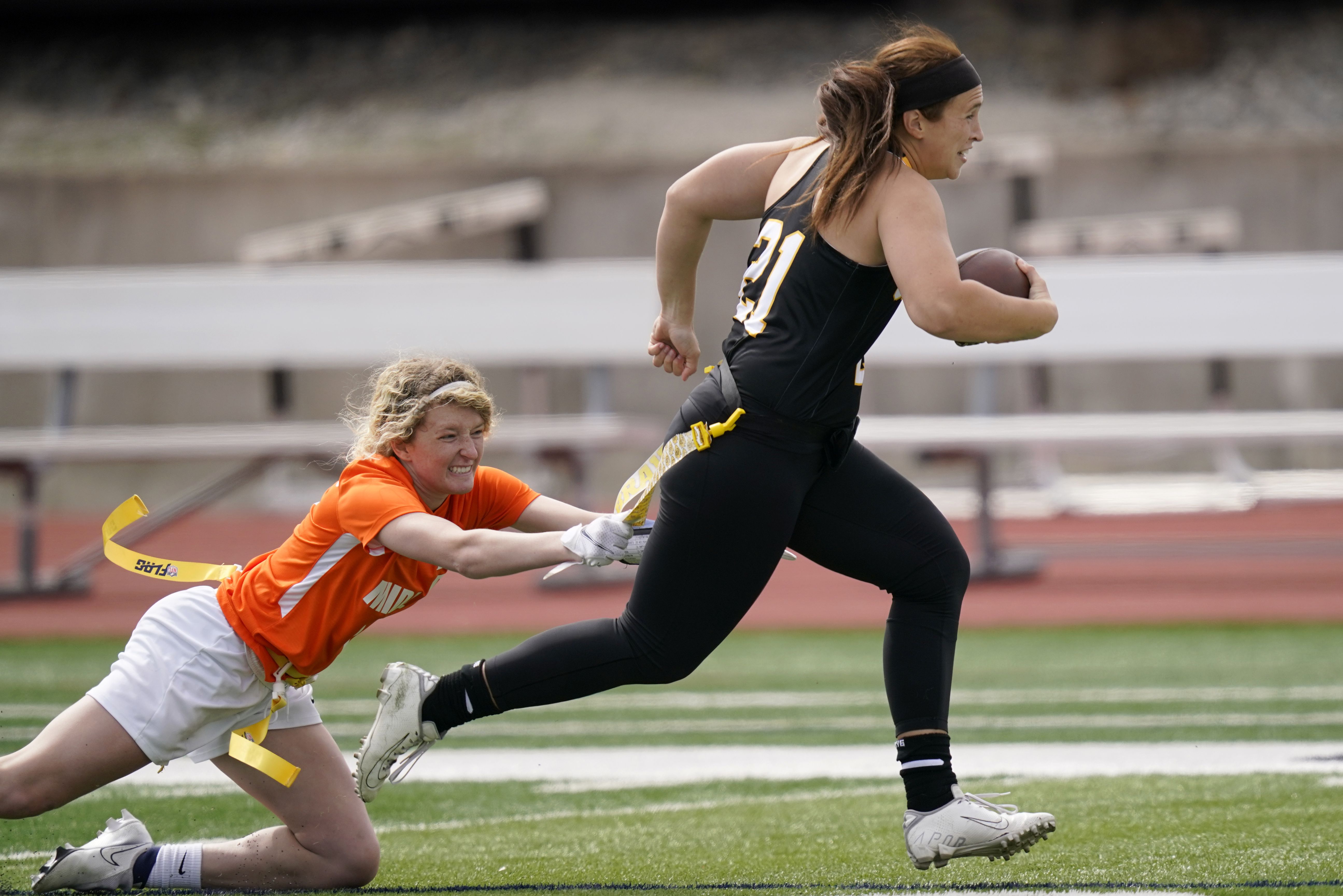 Ottawa quarterback Madysen Carrera is tackled by Midland defender Casey Thompson, left, during an NAIA flag football game in Ottawa, Kan., March 26, 2021. Flag football took a key step toward becoming an Olympic sport in 2028.