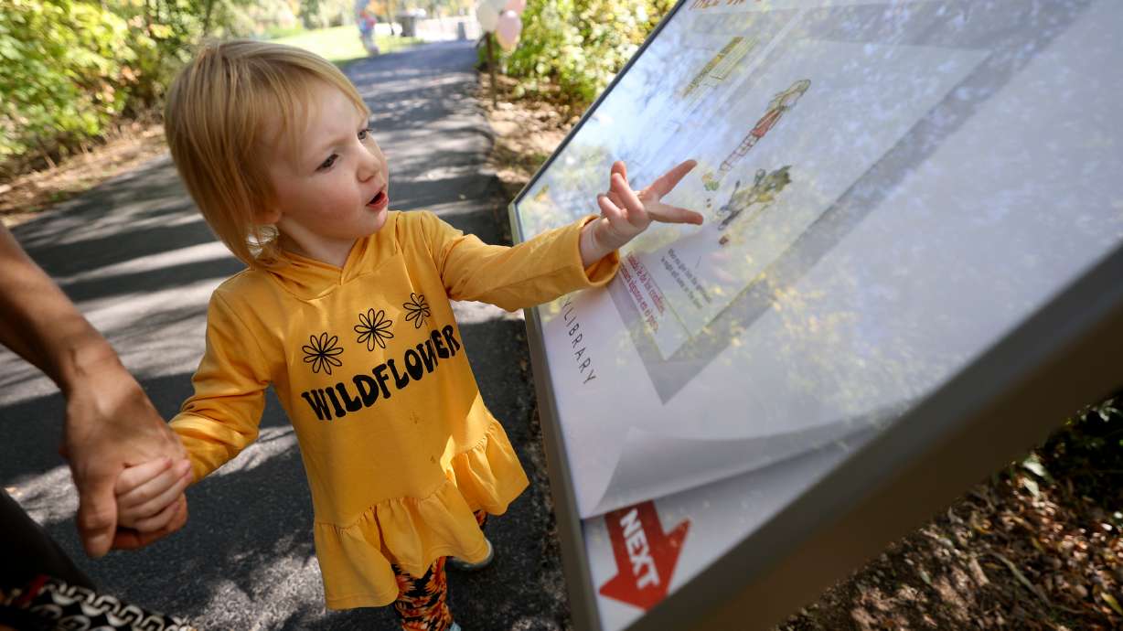 Bentley Barger checks out one of the pages of the featured book, "If You Give a Cat a Cupcake," on the Tale Trail in Murray on Monday. The trail is designed to combine reading and nature.