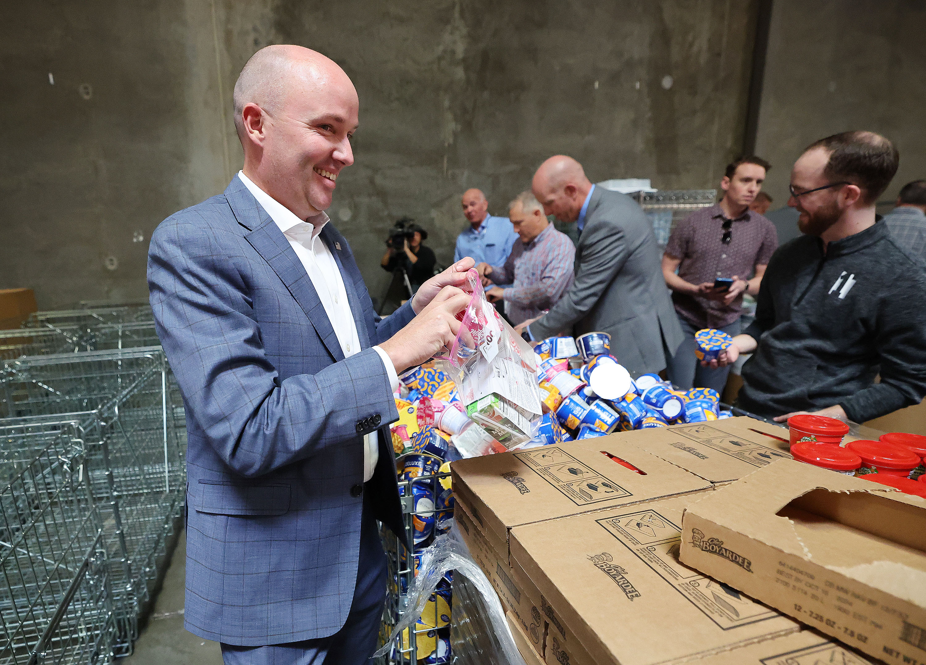 Gov. Spencer Cox puts together weekend food supplies for school children after announcing new state service initiatives at Granite School District in West Valley City on Tuesday.