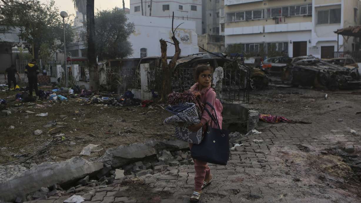 A Palestinian girl carries blankets as she walks past the site of a deadly explosion at al-Ahli hospital, in Gaza City, Oct. 18. Hamas says an Israeli airstrike caused the explosion, but the Israeli military says it was a misfired Palestinian rocket.