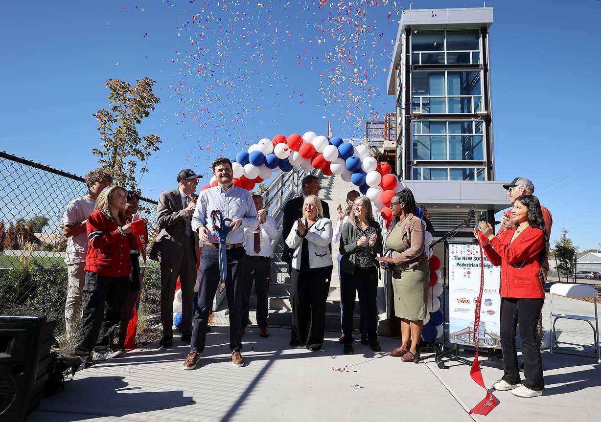 Salt Lake City Councilman Chris Wharton holds giant scissors after cutting the ceremonial ribbon at a ribbon-cutting ceremony for a new pedestrian bridge at 300 North and 490 West, that crosses two Utah Transit Authority and three Union Pacific rail lines, in Salt Lake City on Wednesday. The crossing is on a route heavily used by West High School students walking to and from school.