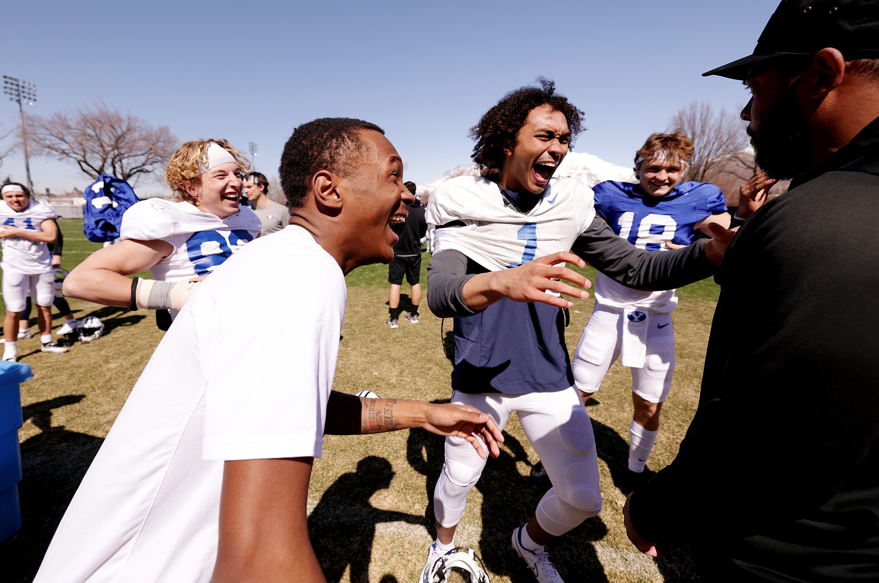 Wide receiver Parker Kingston, cornerback Zion Allen, wide receiver Keanu Hill and quarterback Ryder Burton laugh as they talk with cornerbacks coach Jernaro Gilford after the BYU Cougars football practice in Provo on Friday, March 17, 2023.