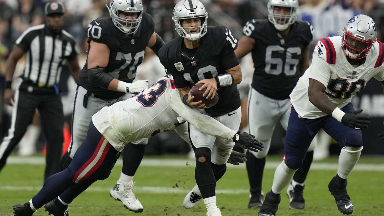 Las Vegas Raiders quarterback Jimmy Garoppolo, center, is hauled down by New England Patriots linebacker Anfernee Jennings during the first half of an NFL football game Sunday, Oct. 15, 2023, in Las Vegas.