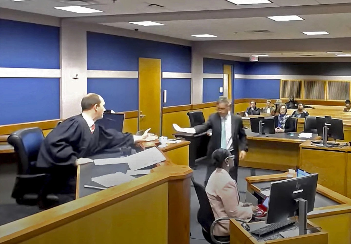 In this frame grab from video, Brian Rafferty, attorney for Sidney Powell, hands Judge Scott McAfee plea documents as Powell attends a hearing on Thursday at the Fulton County Courthouse in Atlanta.