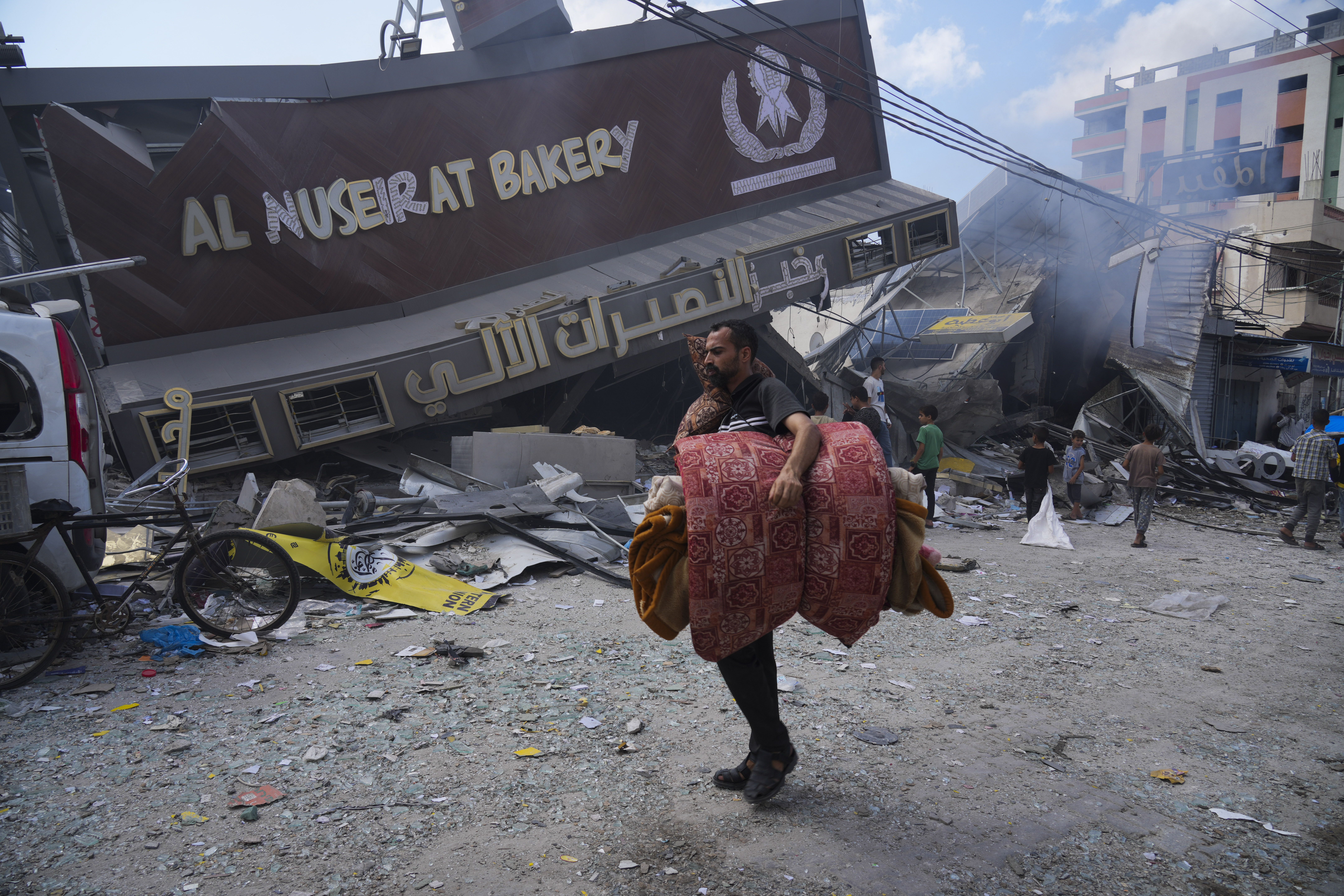 Palestinians walk by the destroyed building of Al Nuseirat Bakery following an Israeli airstrike at Nusseirat refugee camp in the Gaza Strip on Wednesday. Gov. Spencer Cox says he's unsure whether Palestinian refugees will resettle in Utah.