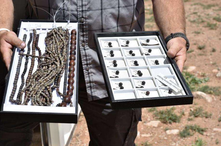 A man holds up cases of jewelry and carvings made from dinosaur bones that were allegedly stolen from federal land.