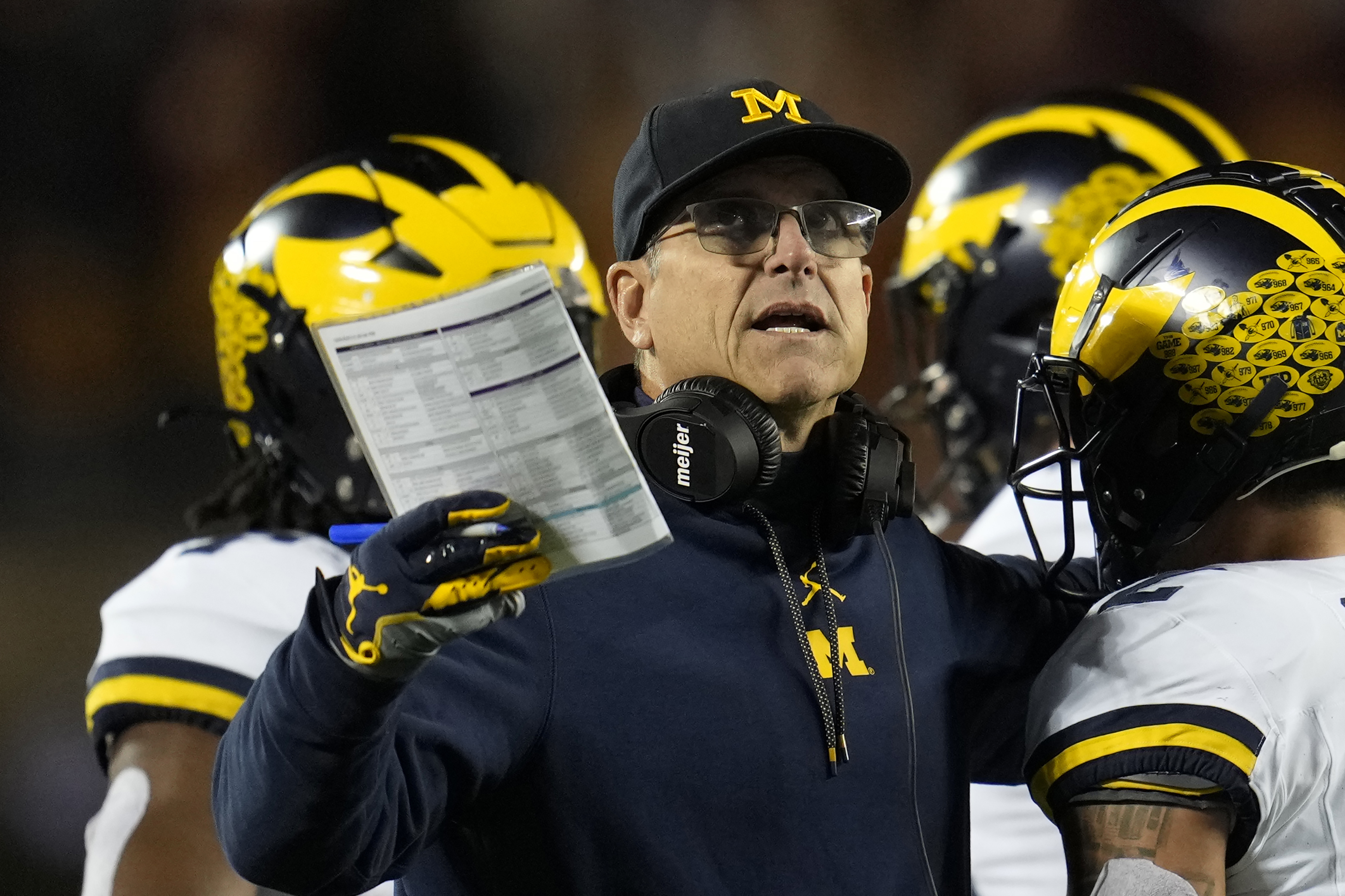 FILE - Michigan head coach Jim Harbaugh stands on the field during the first half of an NCAA college football game against Minnesota Saturday, Oct. 7, 2023, in Minneapolis. The NCAA banned in-person advanced scouting in 1994 in part because not every school could afford to do it. Now Michigan is being investigated by the NCAA for a sign-stealing scheme that allegedly involved people secretly being sent to record opponents’ games. No. 2 Michigan and the Big Ten acknowledged the investigation Thursday, Oct. 19, 2023. 
