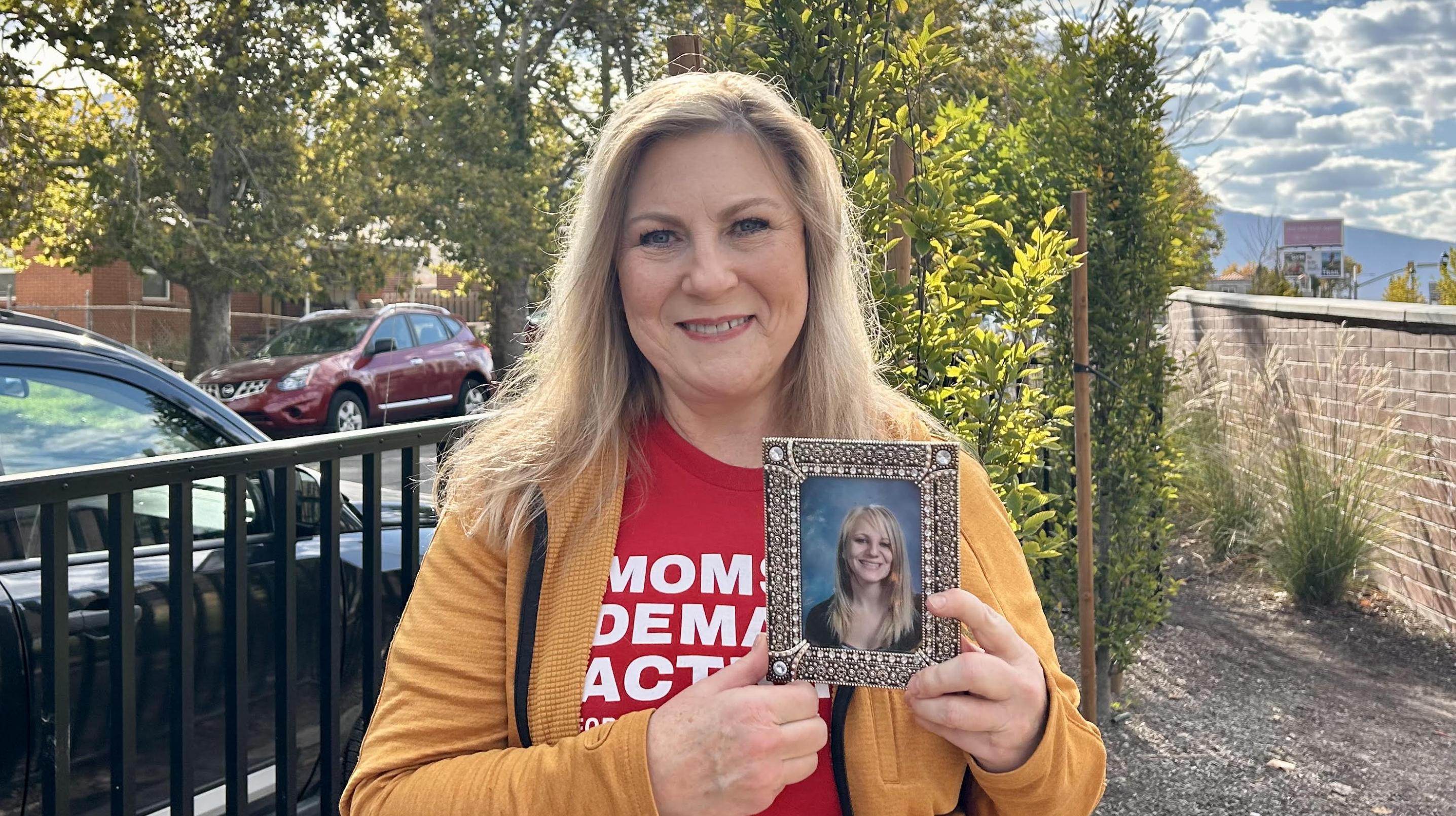 In Millcreek on Saturday, gun violence survivor Carolyn Tuft holds up a photo of her daughter, Kirsten, who died in a Salt Lake shooting in 2007. The Gun Violence Prevention Center of Utah planted 456 daffodils in the Millcreek City Garden on Saturday.