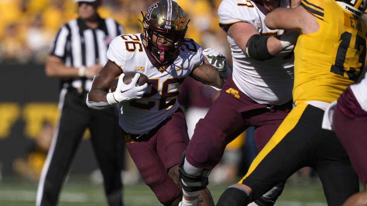 Minnesota offensive lineman Quinn Carroll (77) blocks Iowa defensive end Joe Evans (13) as Minnesota running back Zach Evans (26) runs the ball during the first half of an NCAA college football game, Saturday, Oct. 21, 2023, in Iowa City, Iowa.