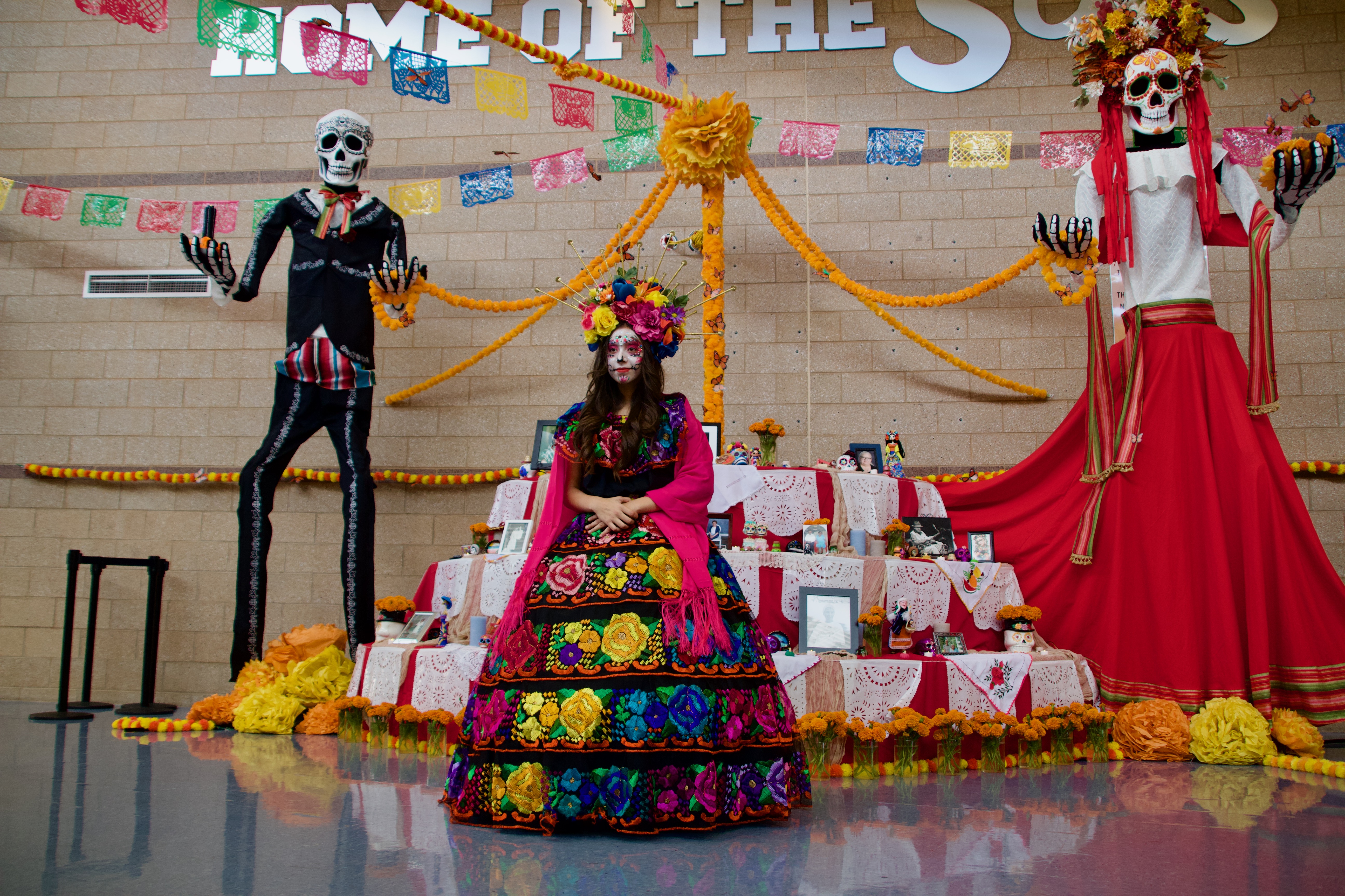 Aleni Salgado, 12, poses for a photo in front of an altar at Día de los Muertos en Ogden at Ben Lomond High School on Saturday.
