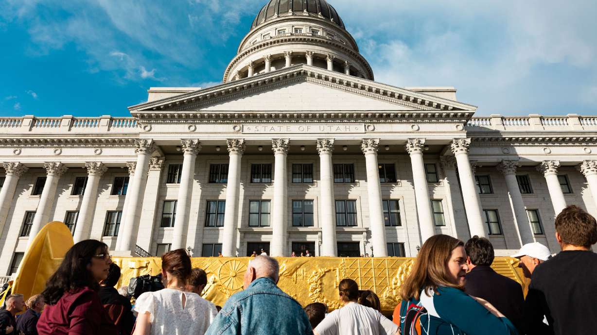 Attendees step up to see the Golden Spike Monument after its arrival in front of the state Capitol in Salt Lake City on Monday. The 43-foot-tall golden spike was commissioned as a public art piece by the Golden Spike Foundation.