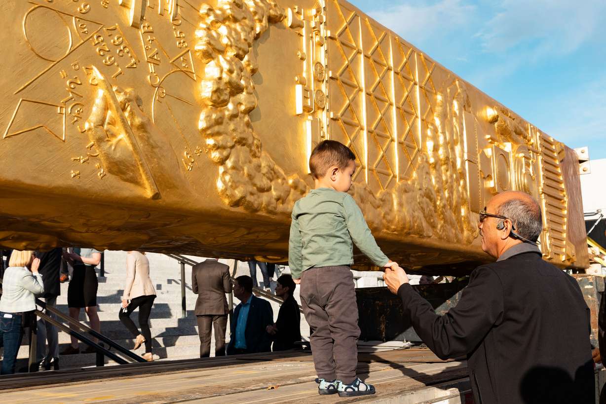 Terence Chen holds 2-year-old Kayce Chen’s hand as he walks next to the Golden Spike Monument after it’s arrival in front of the Utah state Capitol in Salt Lake City on Oct. 23, 2023. The Utah Legislature voted Wednesday to make its future home in Brigham City one of two new state monuments.