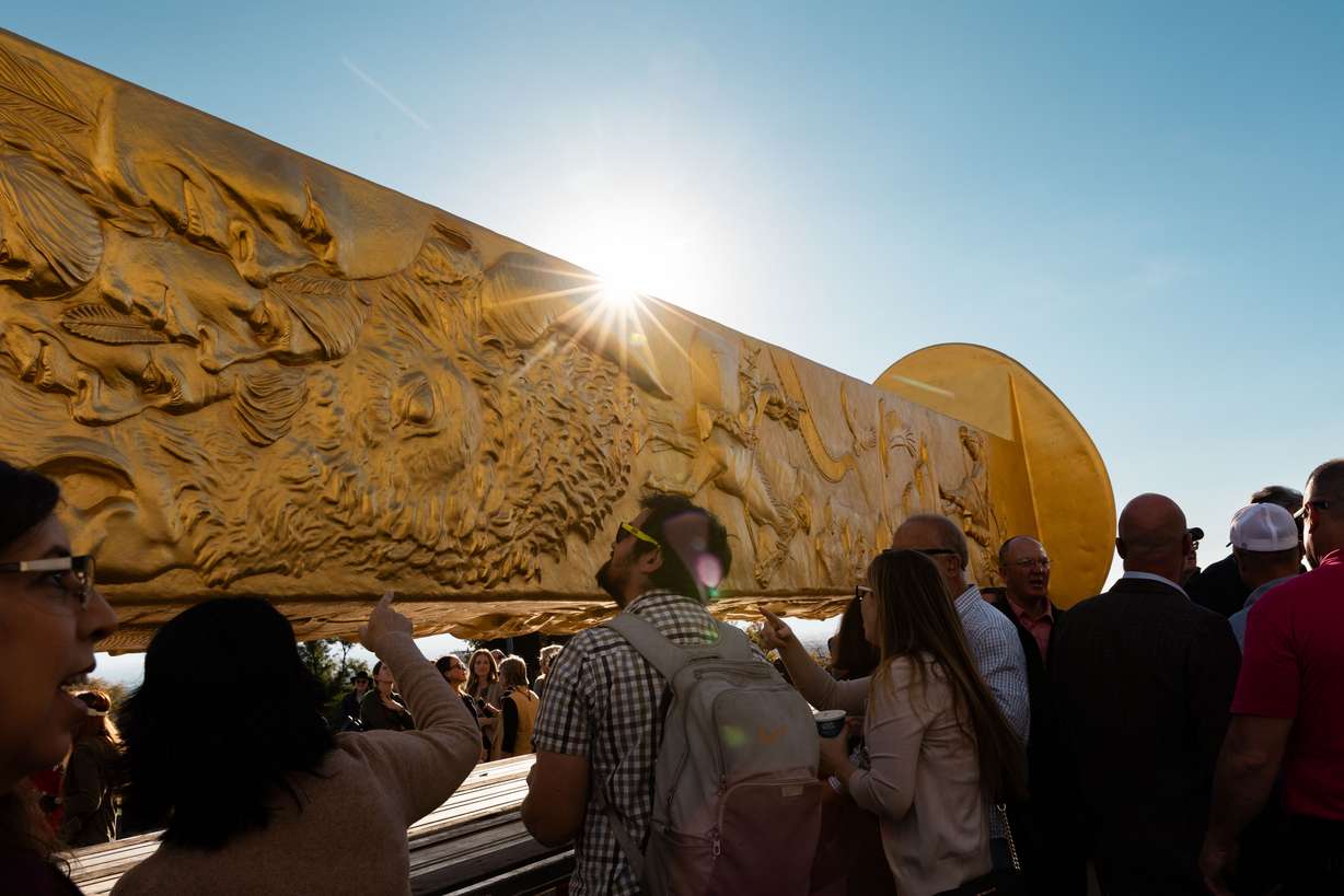 Attendees step up to see the Golden Spike Monument after its arrival in front of the Utah state Capitol in Salt Lake City on Monday. The 43-foot-tall golden spike was commissioned as a public art piece by the Golden Spike Foundation to honor the tens of thousands of railroad workers who built the transcontinental railroad.