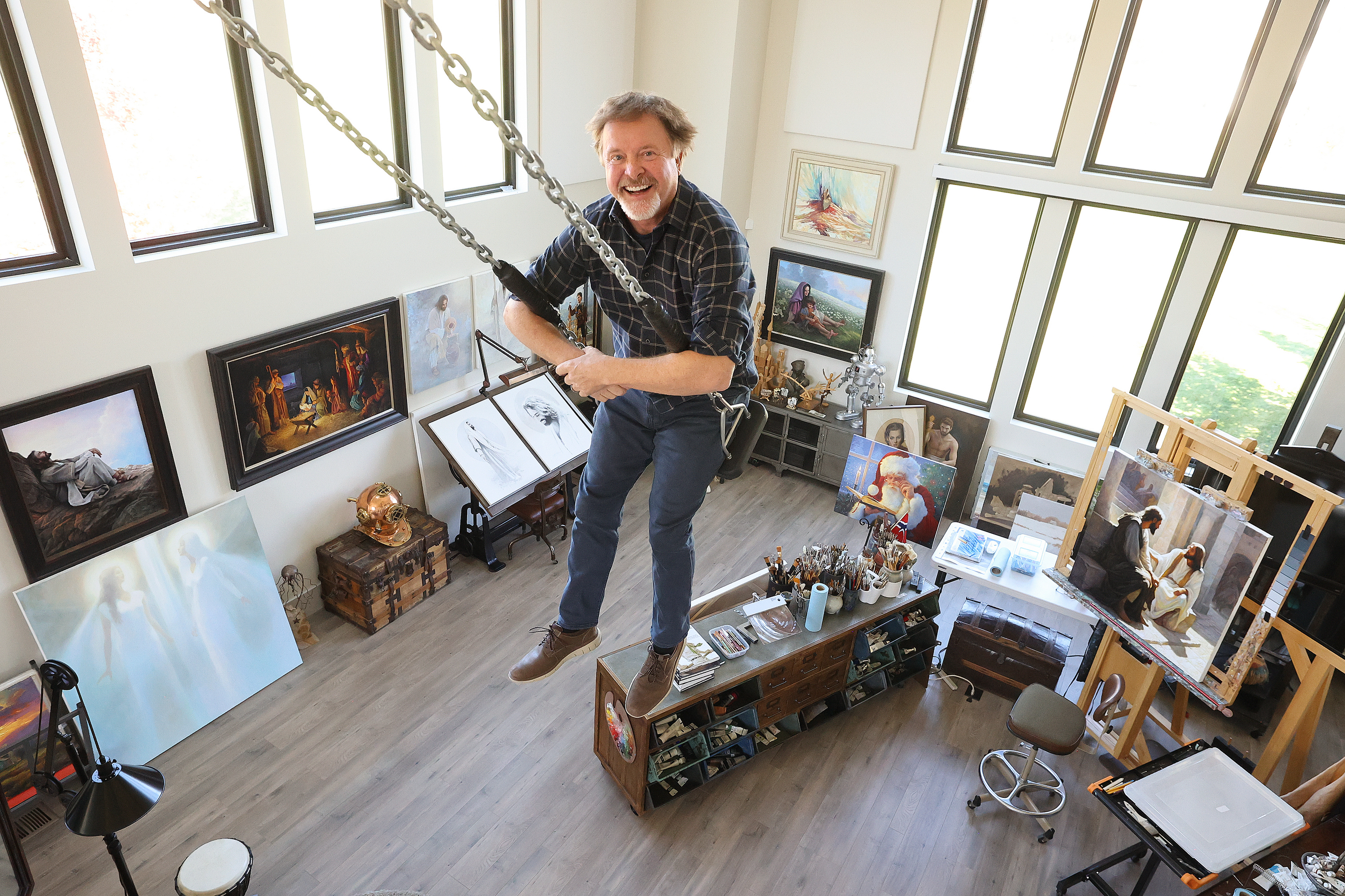 Artist Greg Olsen poses for a portrait on a swing in his home studio in Heber Oct. 9.