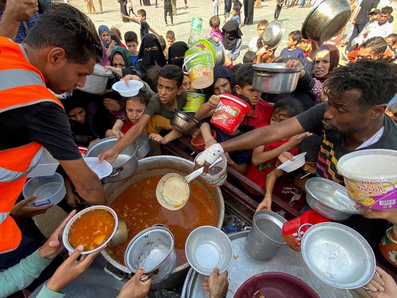 Palestinians, who fled their houses due to Israeli strikes, gather to get their share of charity food offered by volunteers, amid food shortages, at a UN-run school where they take refuge, in Rafah, in the southern Gaza Strip, Sunday.