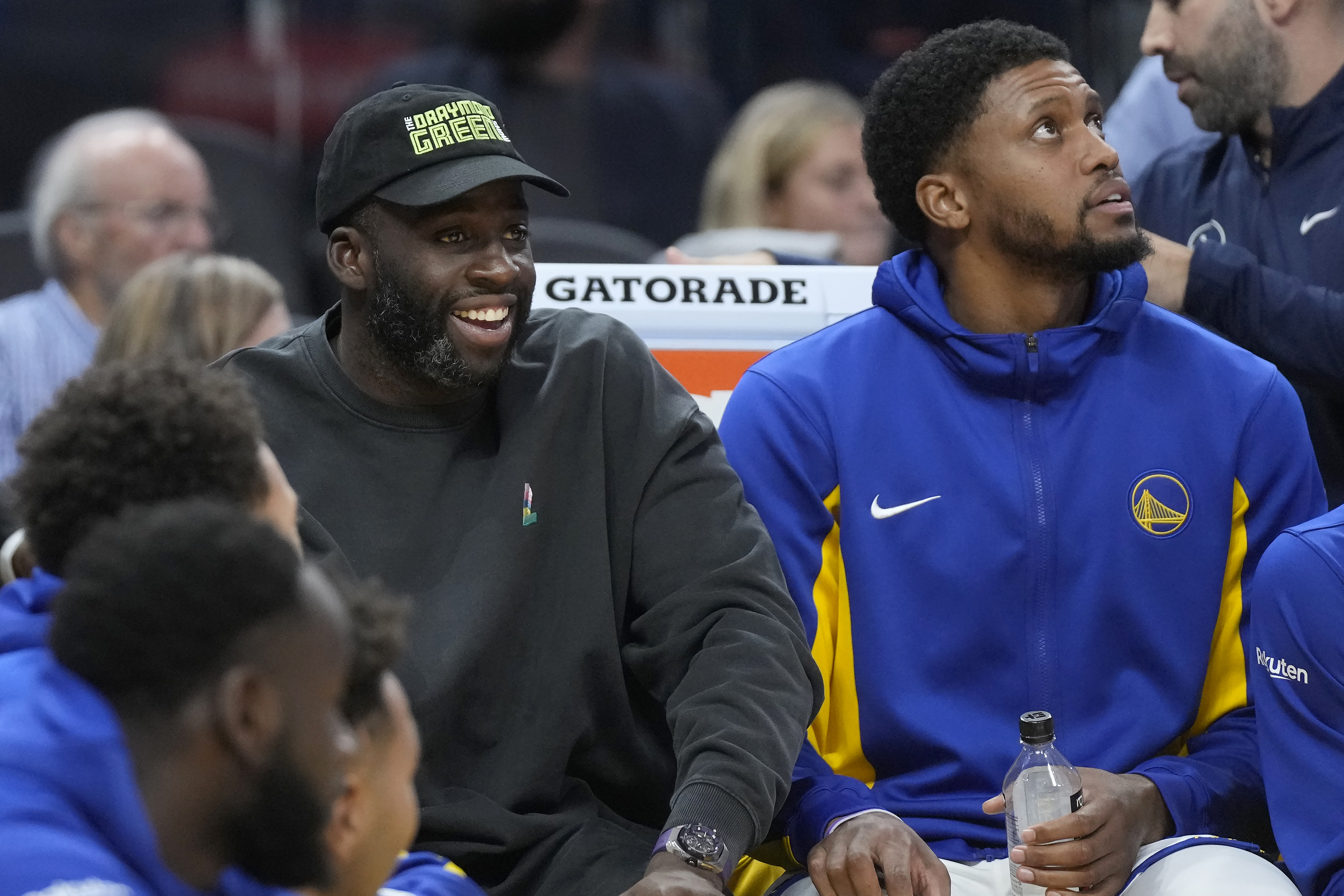 Injured Golden State Warriors forward Draymond Green, left, watches from the bench next to forward Rudy Gay during the first half of an NBA preseason basketball game against the San Antonio Spurs in San Francisco, Friday, Oct. 20, 2023. 
